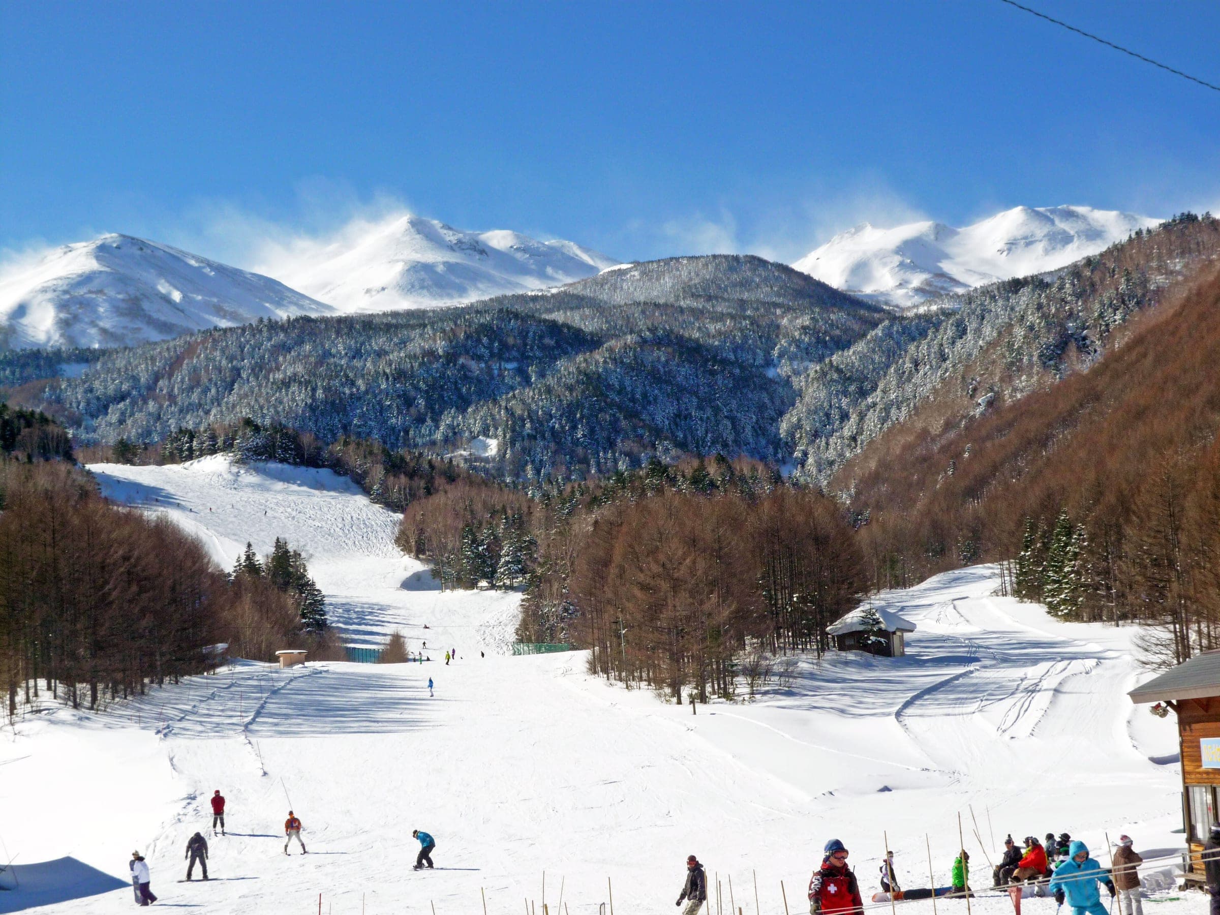 Skiers gather at the base of Mt. Norikura Snow Resort below the white peaks of Mount Norikura