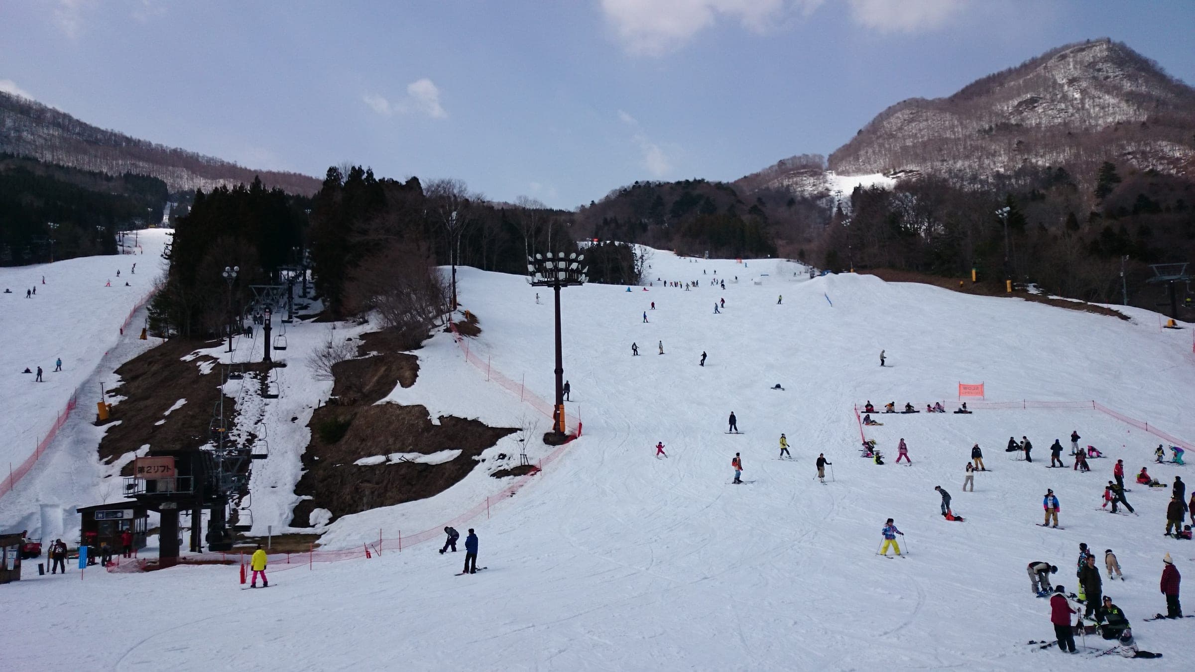 Skiers and snowboarders fill the wide lower slopes of Norn Minakami on a March day