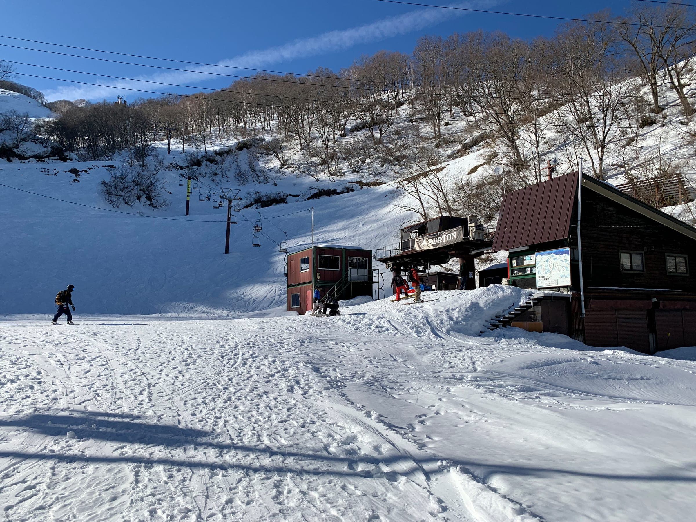 Wooden lodges and a lift hut stand at the snowy base of Seki Onsen Ski Area