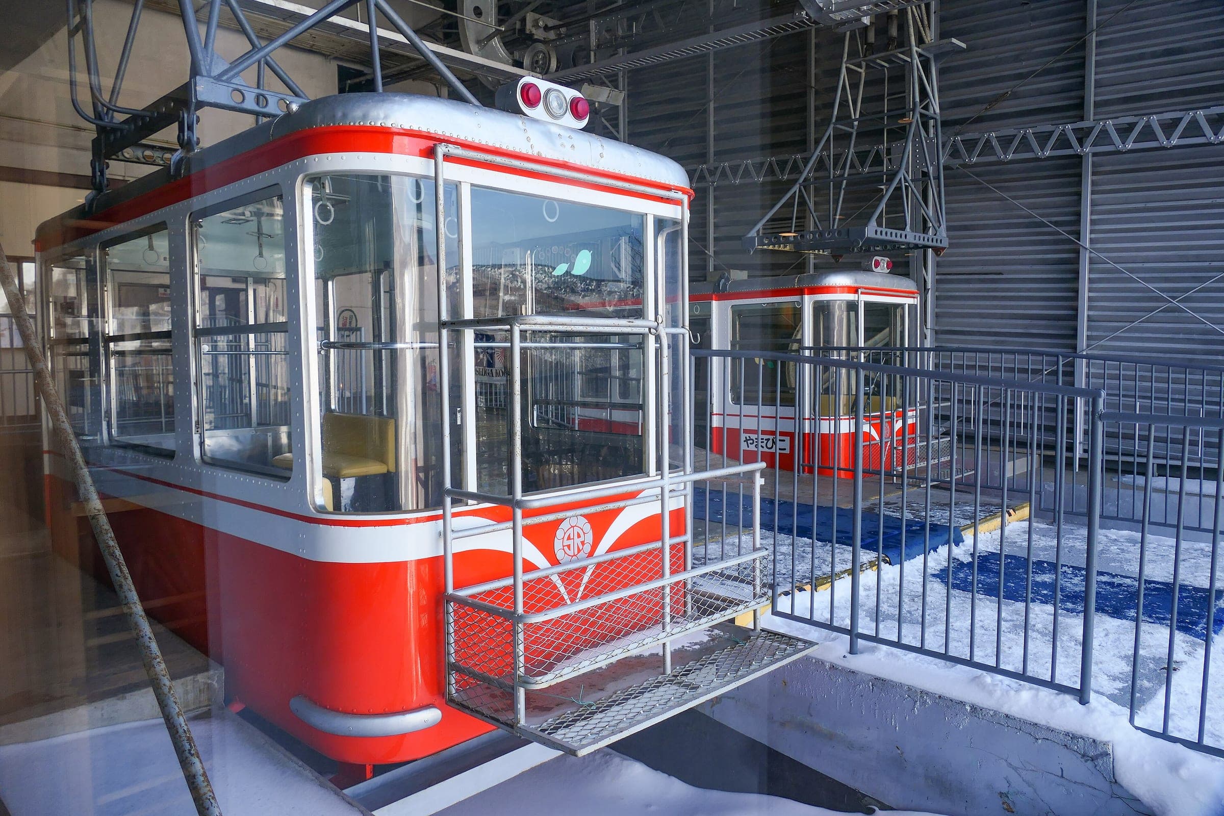 A red Shiga Kogen Ropeway cabin waits in the station at Hasuike before the ride up to Higashidateyama