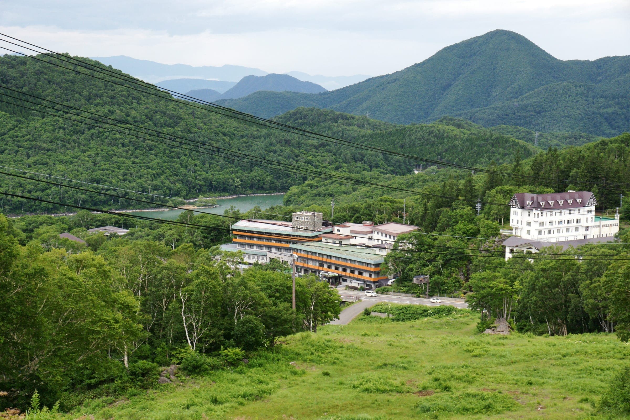 The Maruike hotels and pond sit below the grassed ski slope of Shiga Kogen Maruike in July
