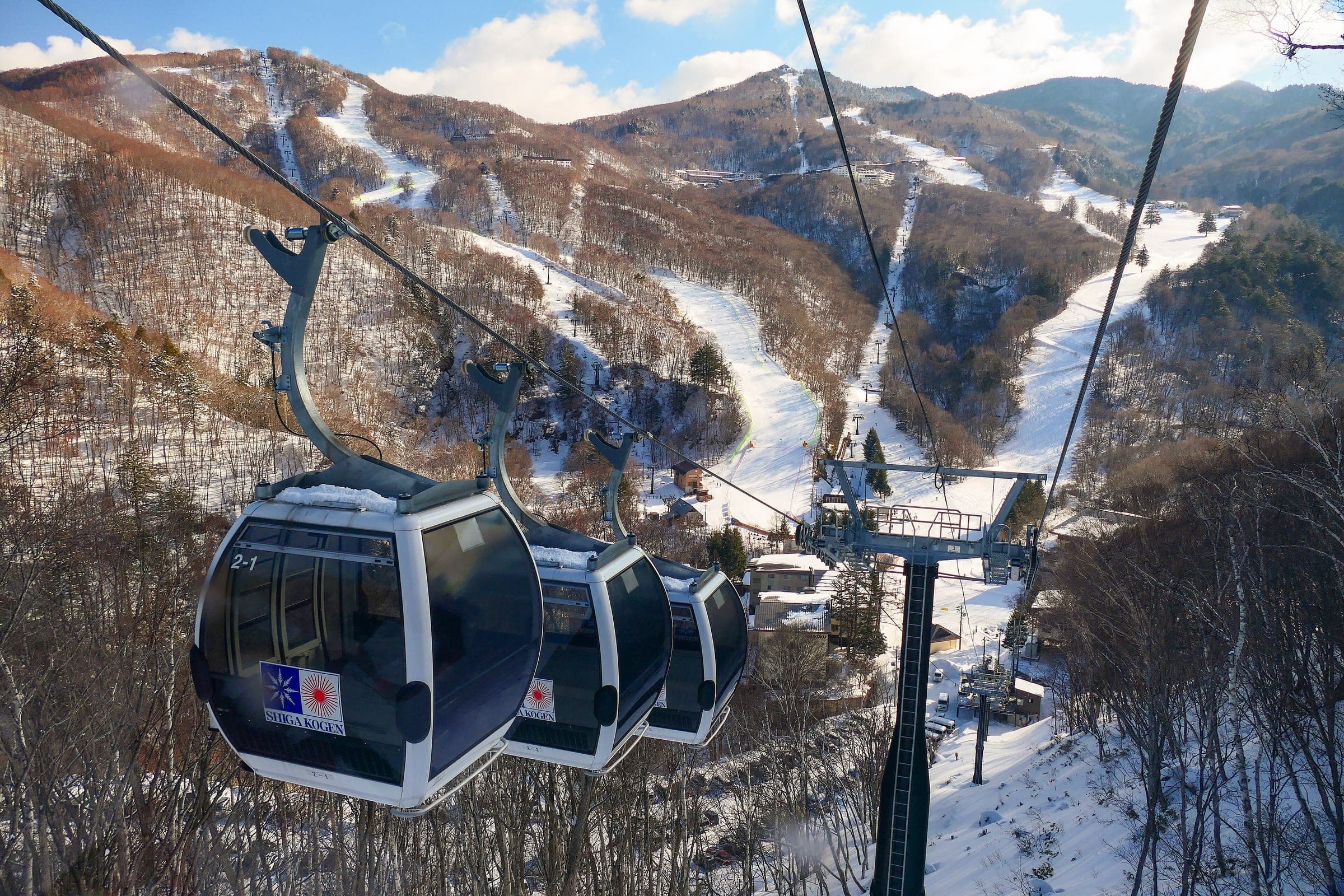 Gondola cabins rise over central Shiga Kogen with the long runs of Nishidateyama behind them