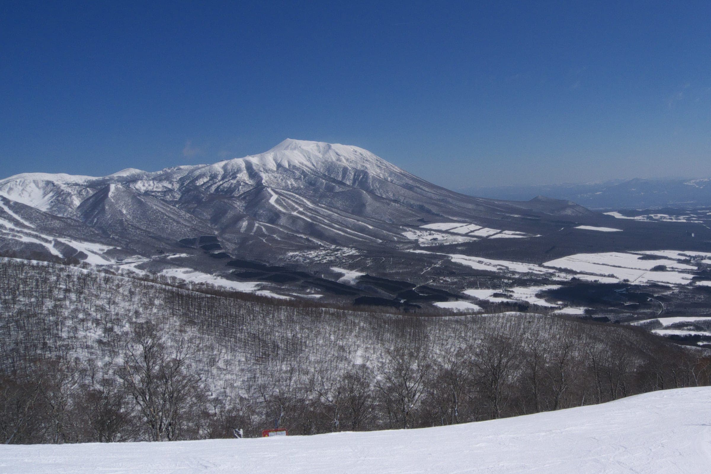 Mount Iwate and Mount Kurakake rise white beyond the upper slopes of Shizukuishi ski area.