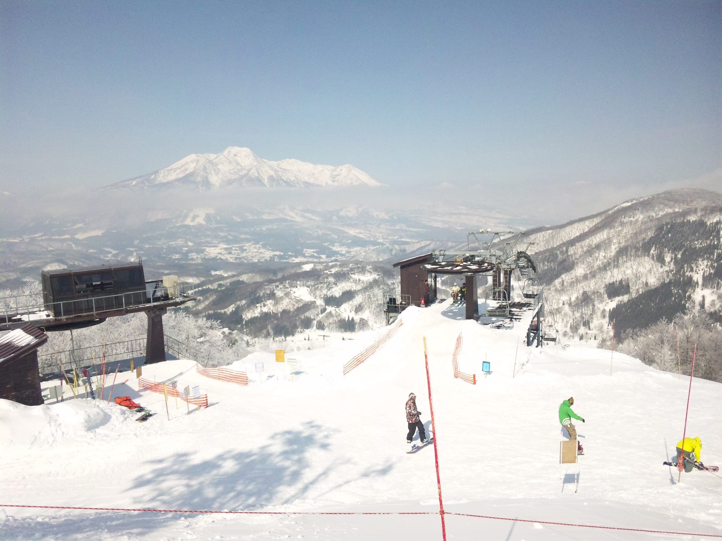 Riders play in the snow at the top of Tangram Ski Circus with Mount Myoko white on the skyline