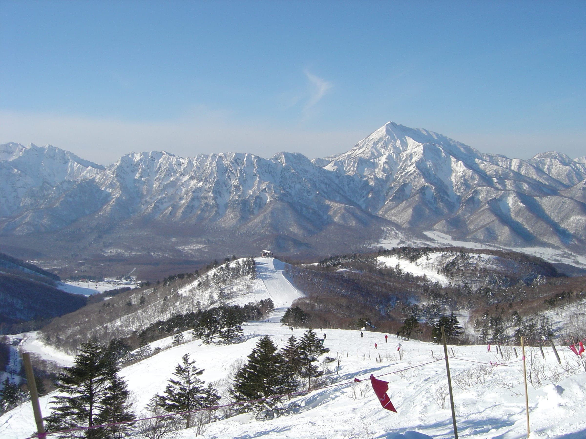 The jagged Togakushi range and Mount Takatsuma tower over the runs of Togakushi on a clear winter day