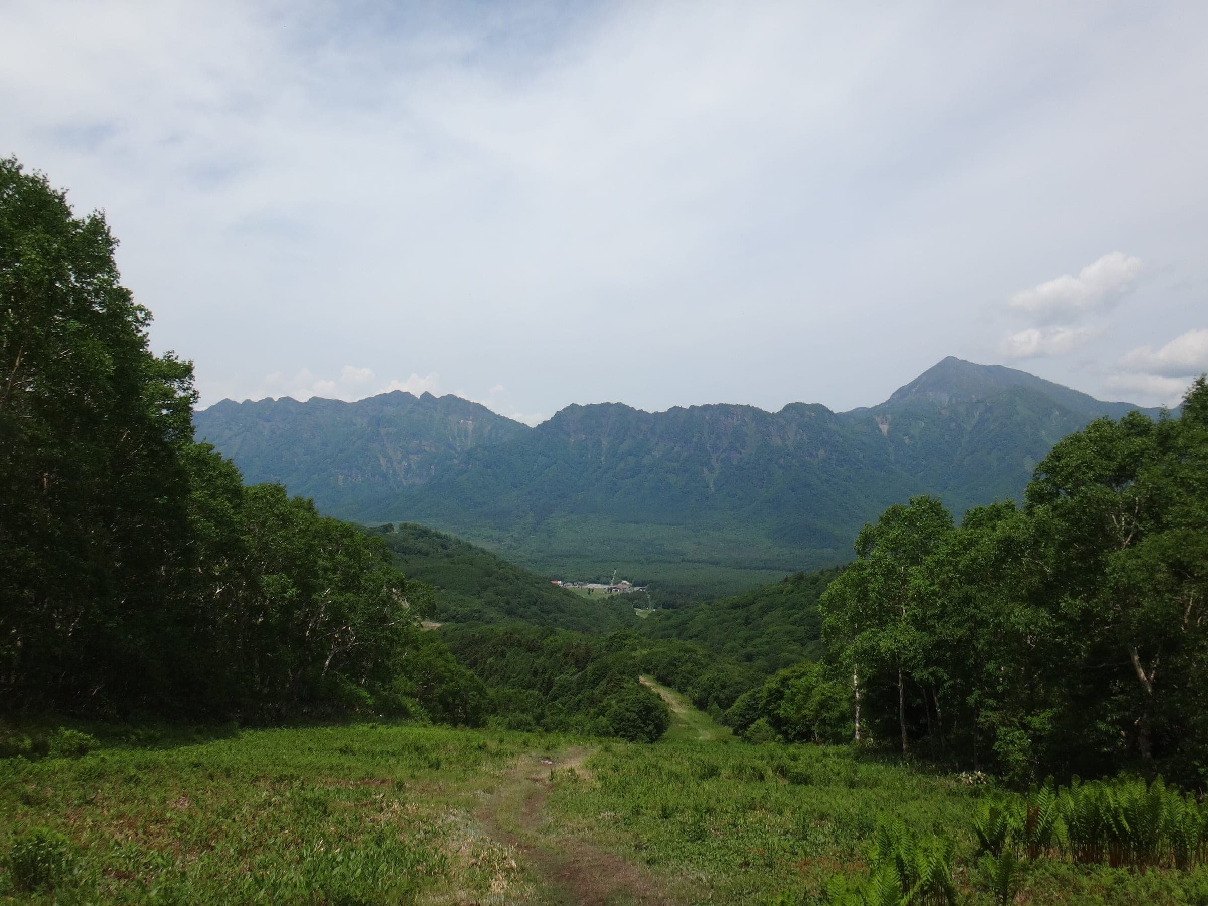 A grassy Togakushi ski run in June looks across to the Togakushi range and Mount Takatsuma