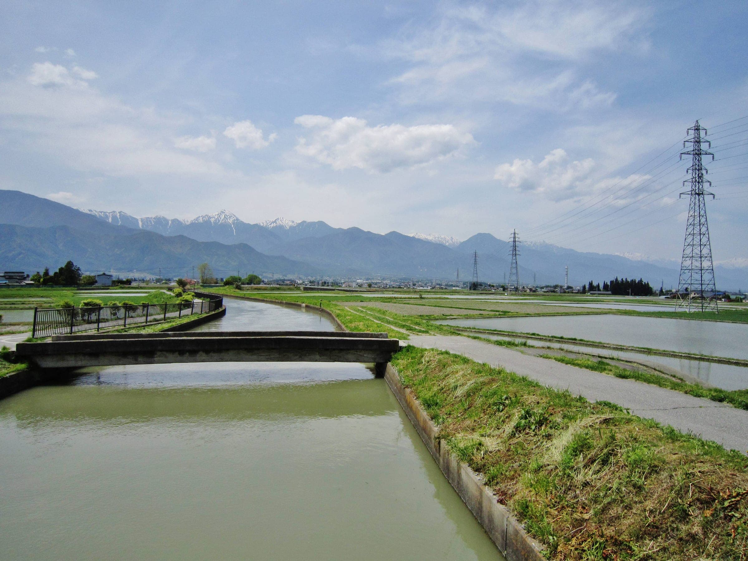 The Jikka Segi irrigation channel runs straight across Azumino toward the snow-capped Northern Alps.