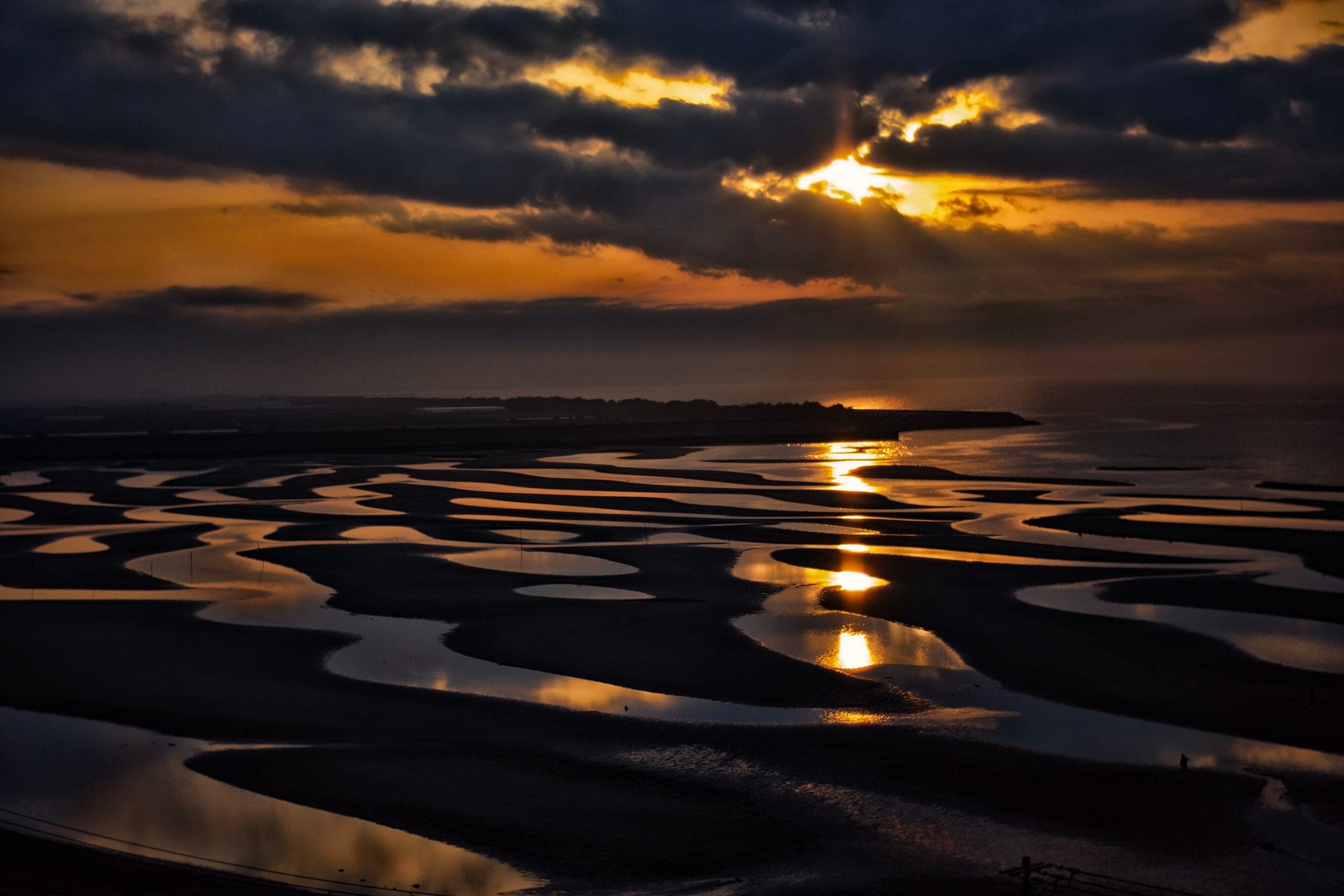The sun sets over the rippled tidal flats of Matama Beach on the Kunisaki Peninsula's north coast.