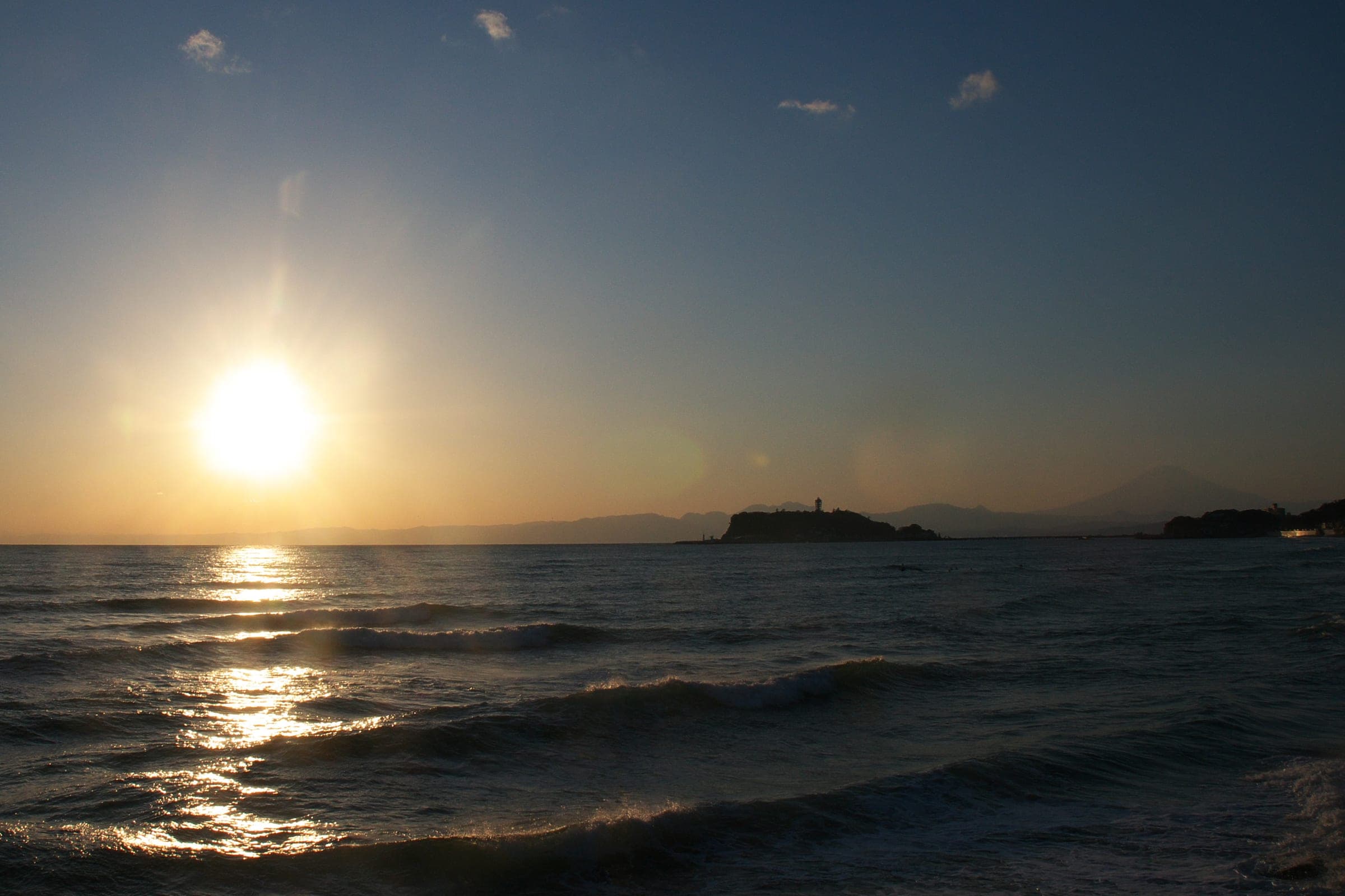 The sun drops toward Enoshima and the outline of Mt. Fuji from Shichirigahama Beach in Kamakura.