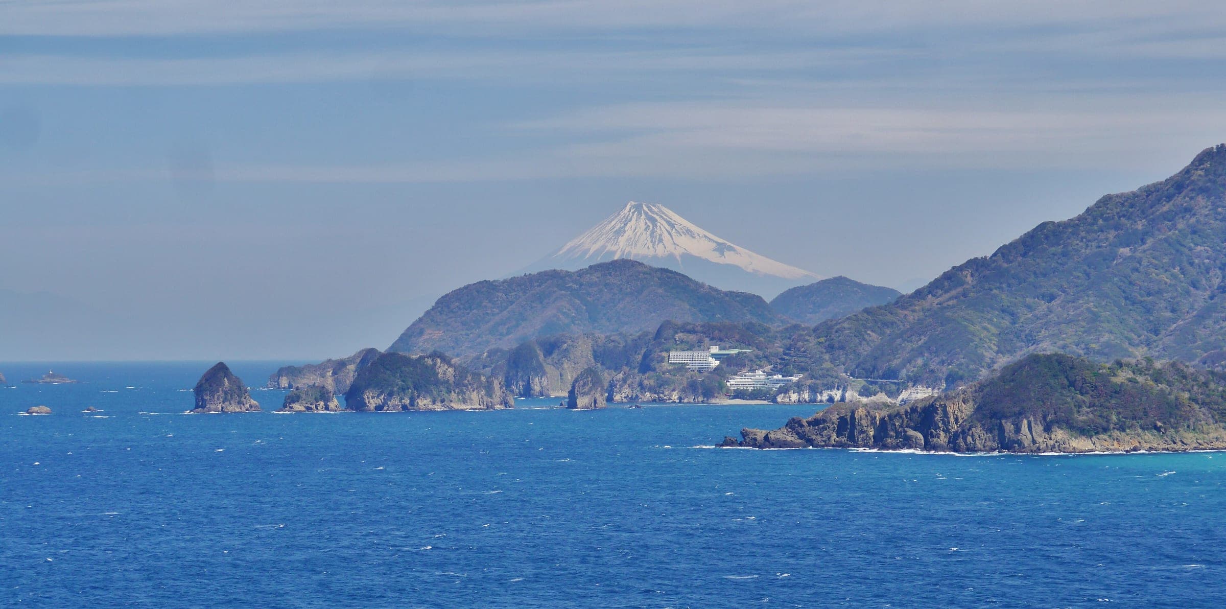 Mt. Fuji stands across Suruga Bay above the rocky headlands of the Nishiizu coast.