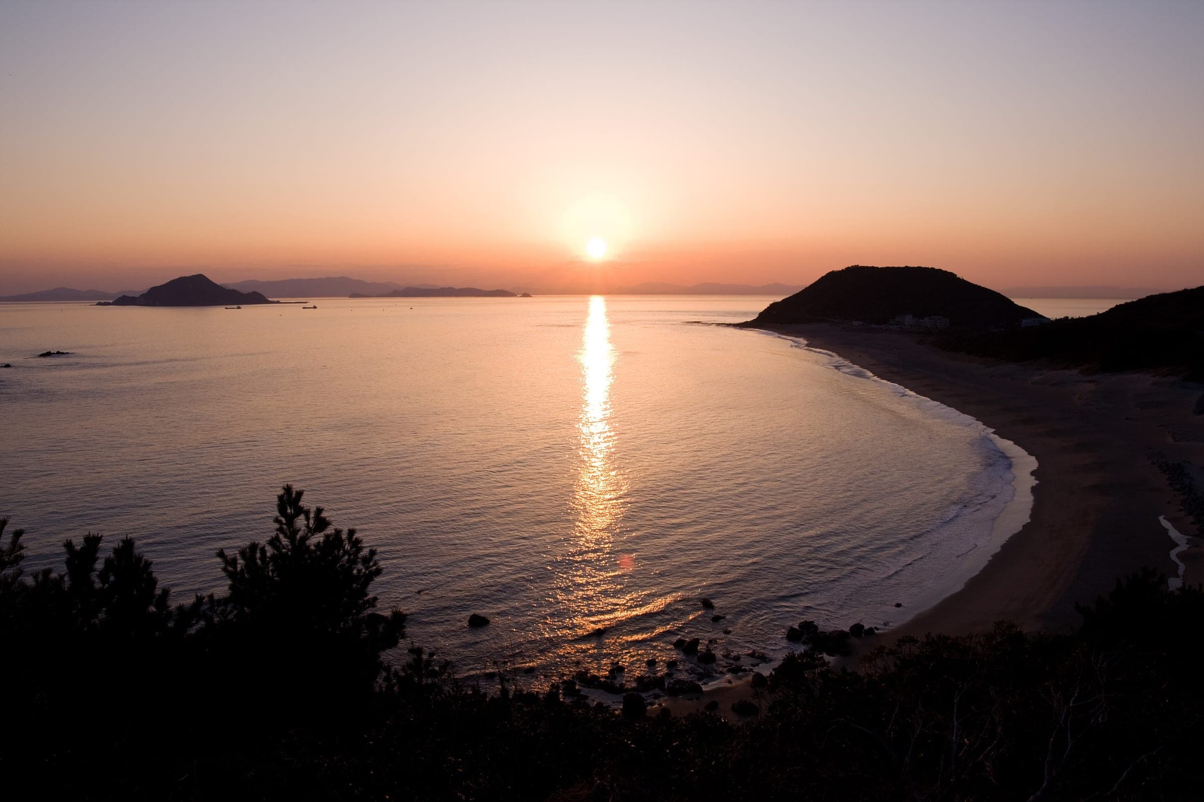 The sun sets over Ise Bay beyond the beach at Cape Irago on a February evening