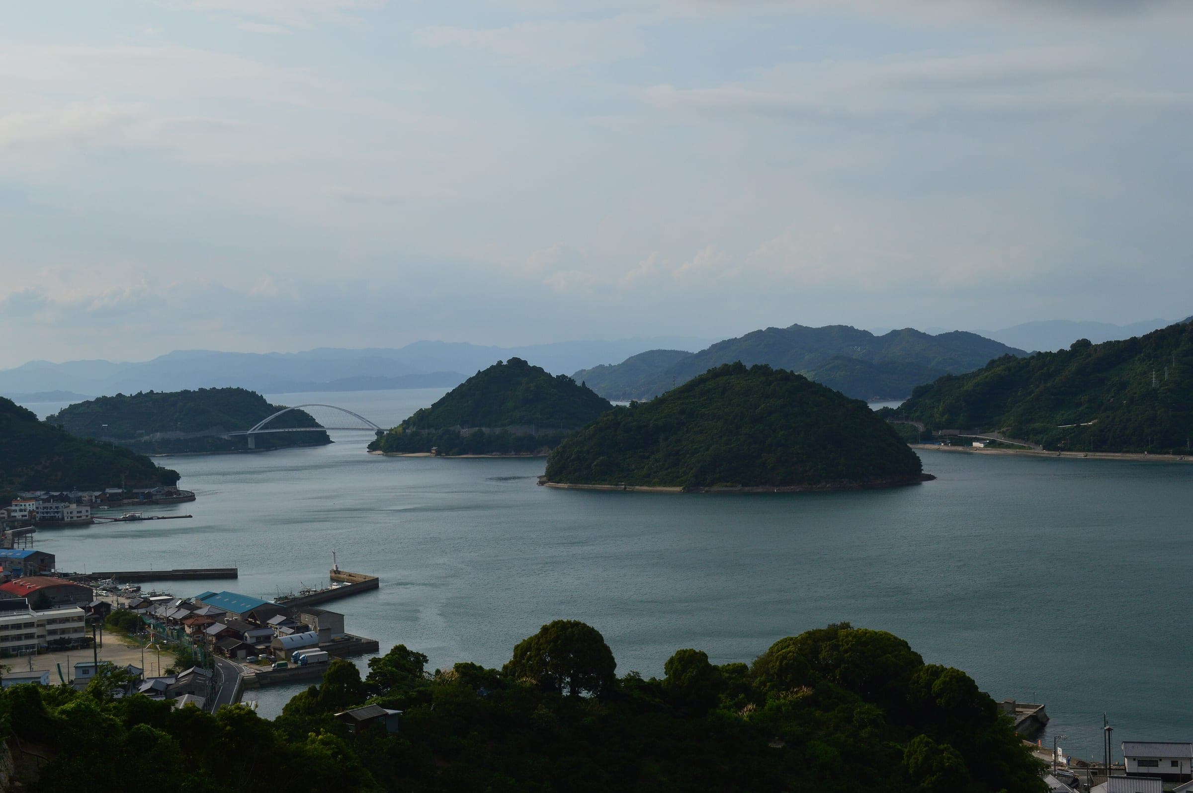 Small islands and the arched Naka-no-Seto Bridge sit in the channel by Okamurajima on the Tobishima Kaido.