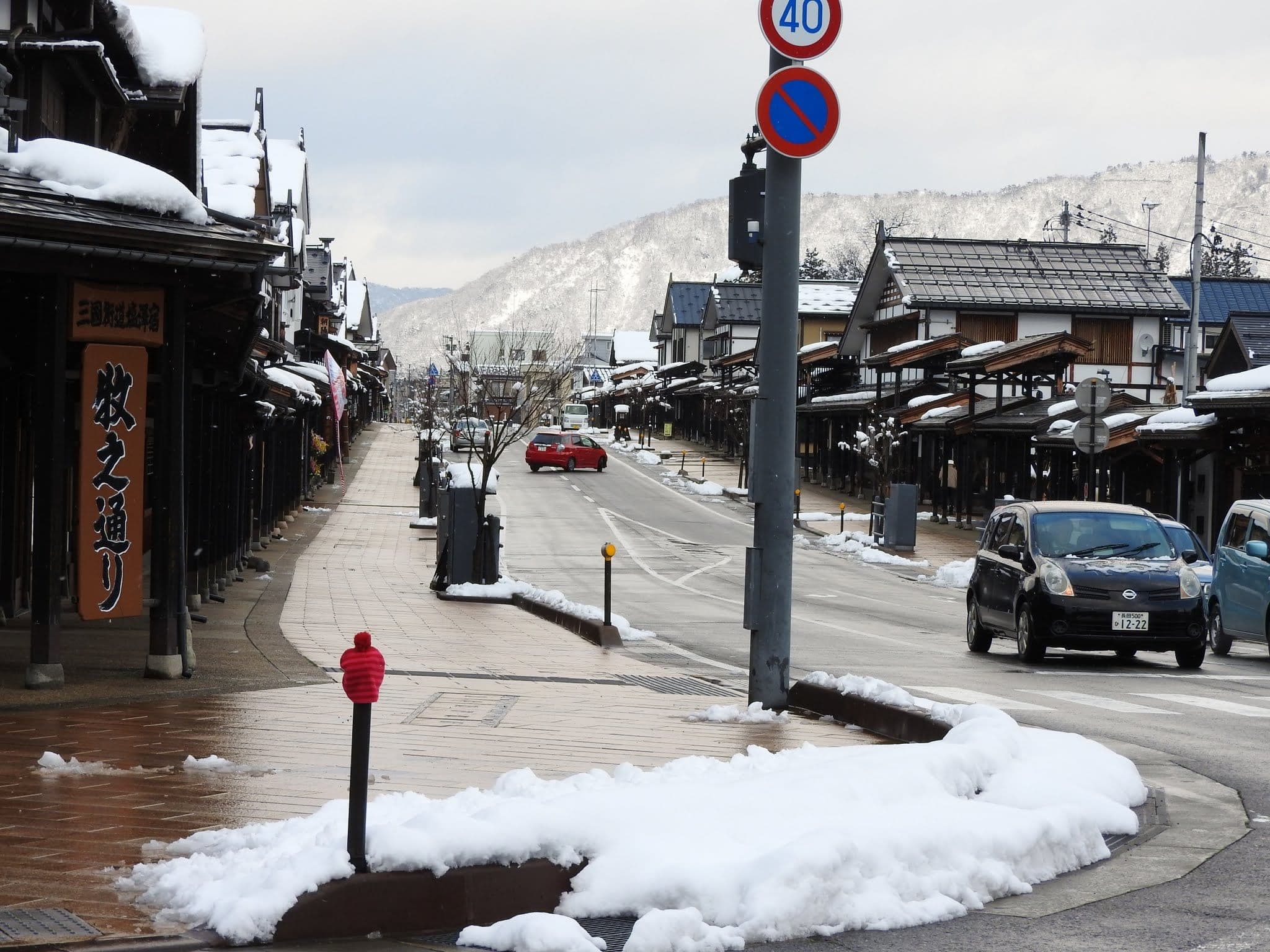 Snow edges the timber arcades of Bokushi-dori in Shiozawa below white hills in January