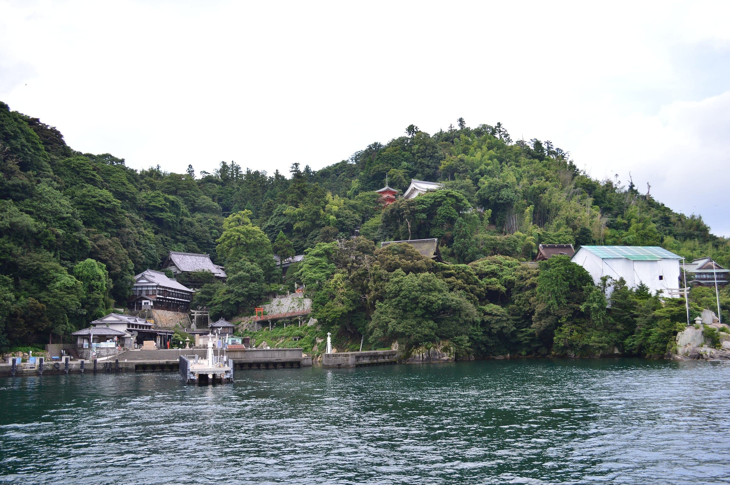 Shrine and temple roofs climb the green slope of Chikubu Island above its boat landing
