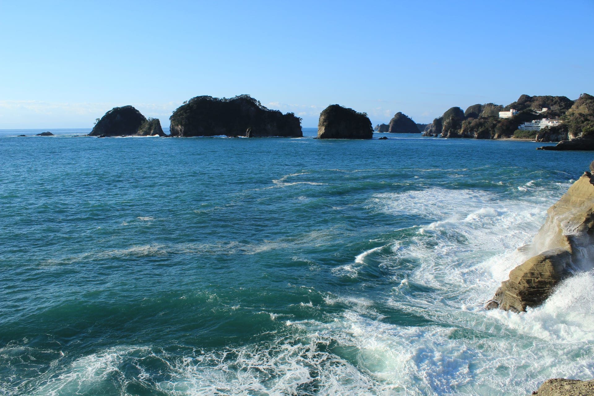 Surf churns below the cliffs at Dogashima as the Sanshirojima islets stand offshore in Nishiizu.