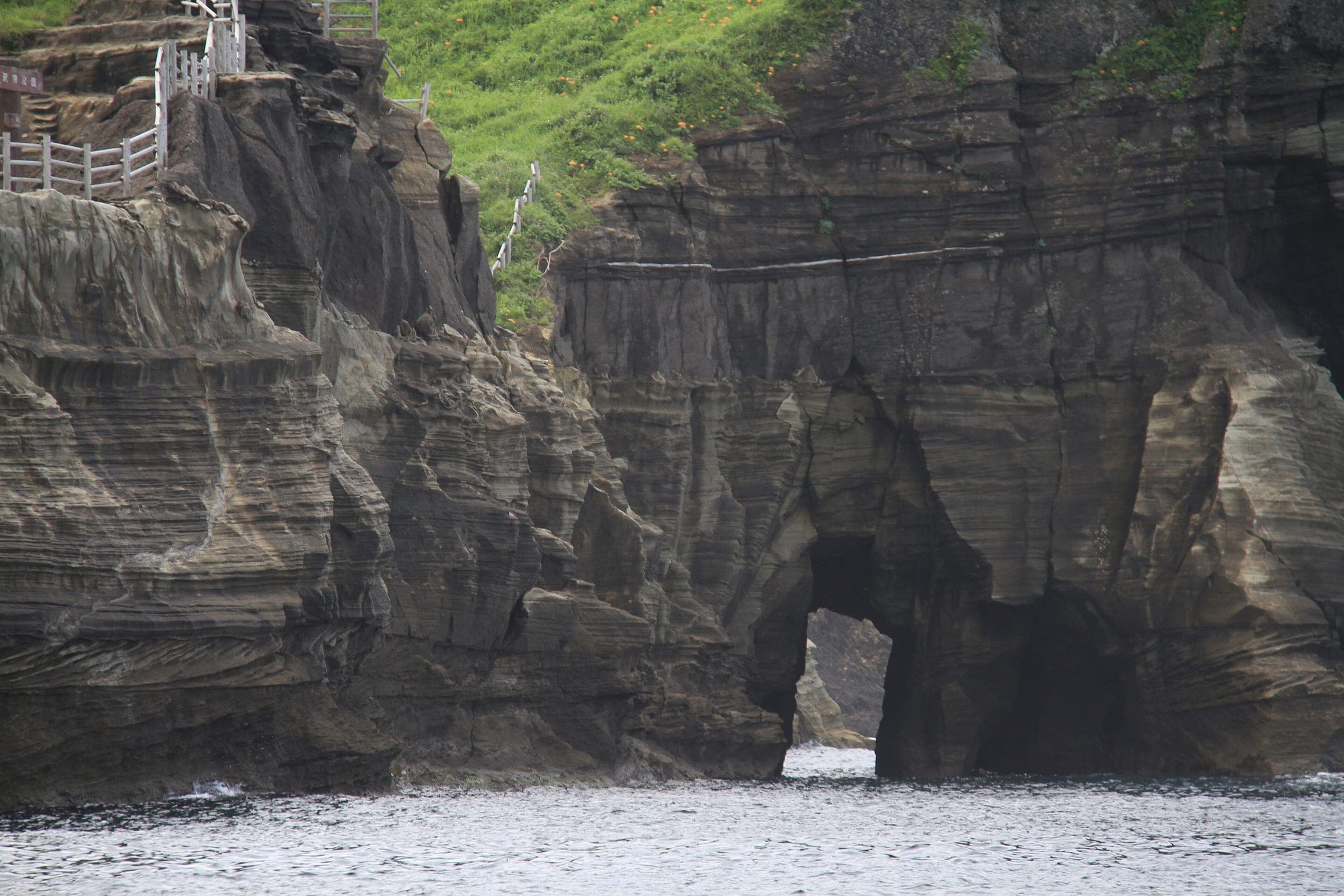 Layered white tuff cliffs at Dogashima open into a sea arch above the water.