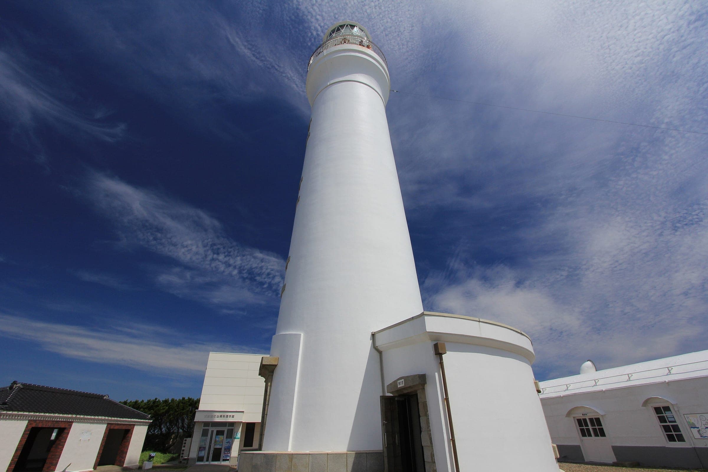 The white brick tower of Inubosaki Lighthouse rises under a streaked summer sky in Choshi.