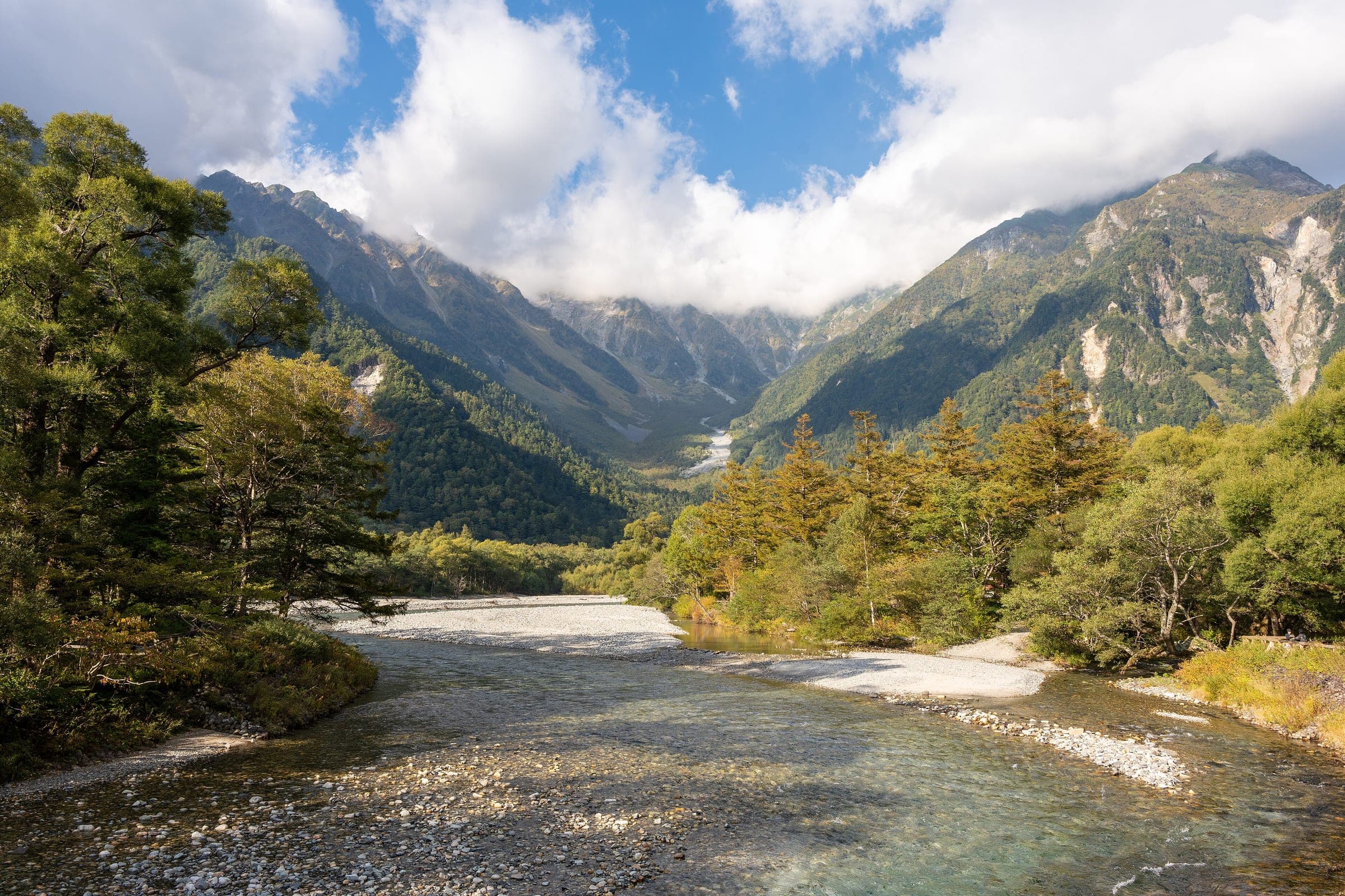 The Azusa River runs clear over pale gravel below the Hotaka peaks at Kamikochi in October.