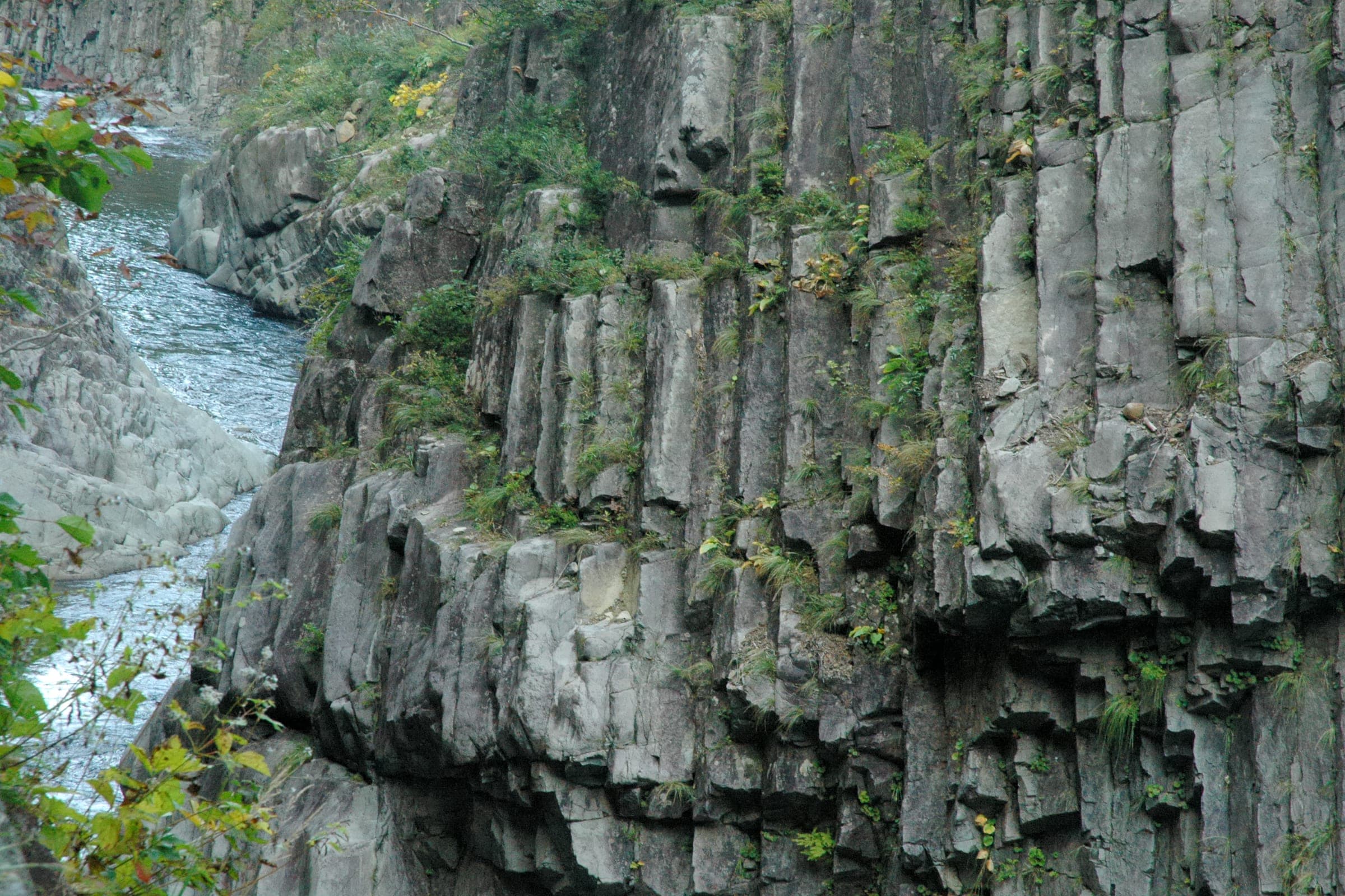 Columns of grey volcanic rock form the sheer walls of Kiyotsu Gorge above the river