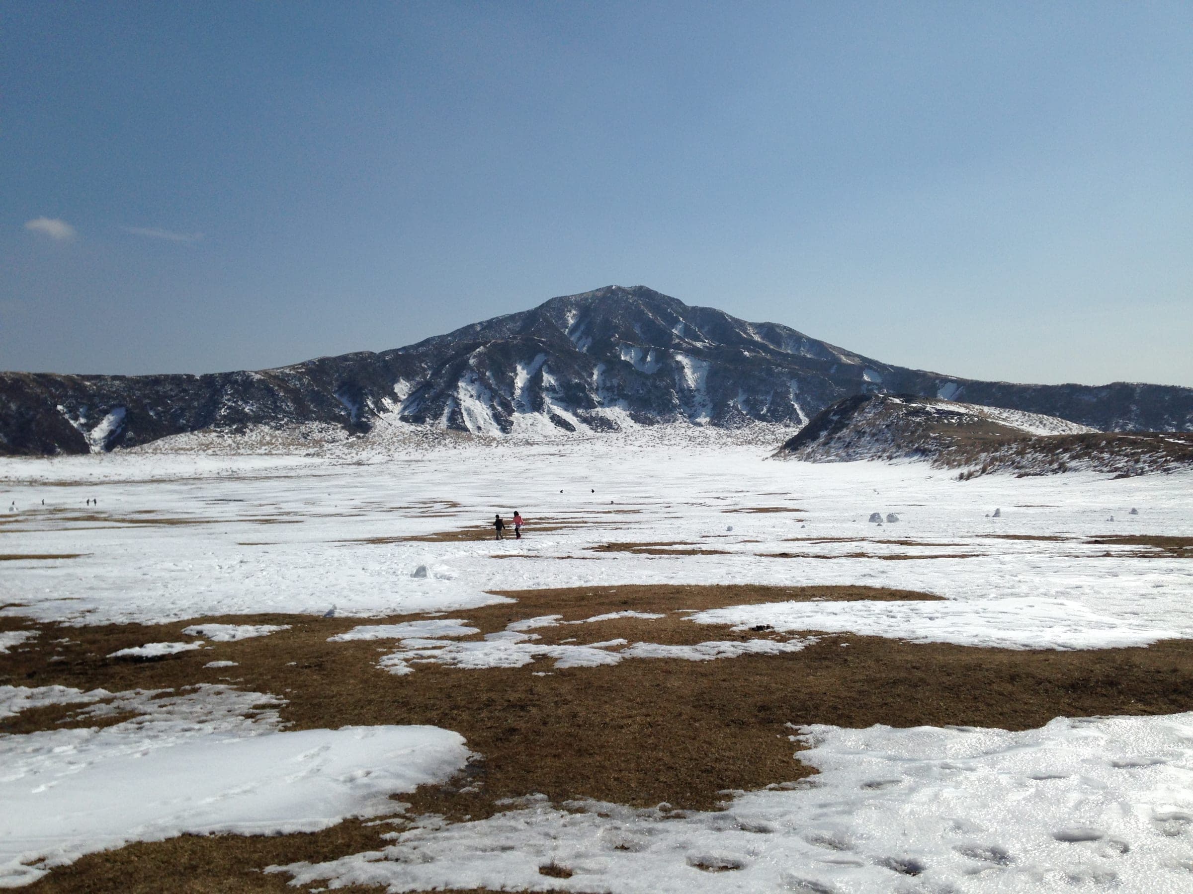 Snow covers the Kusasenri meadow below the dark slopes of Mount Eboshidake in February.