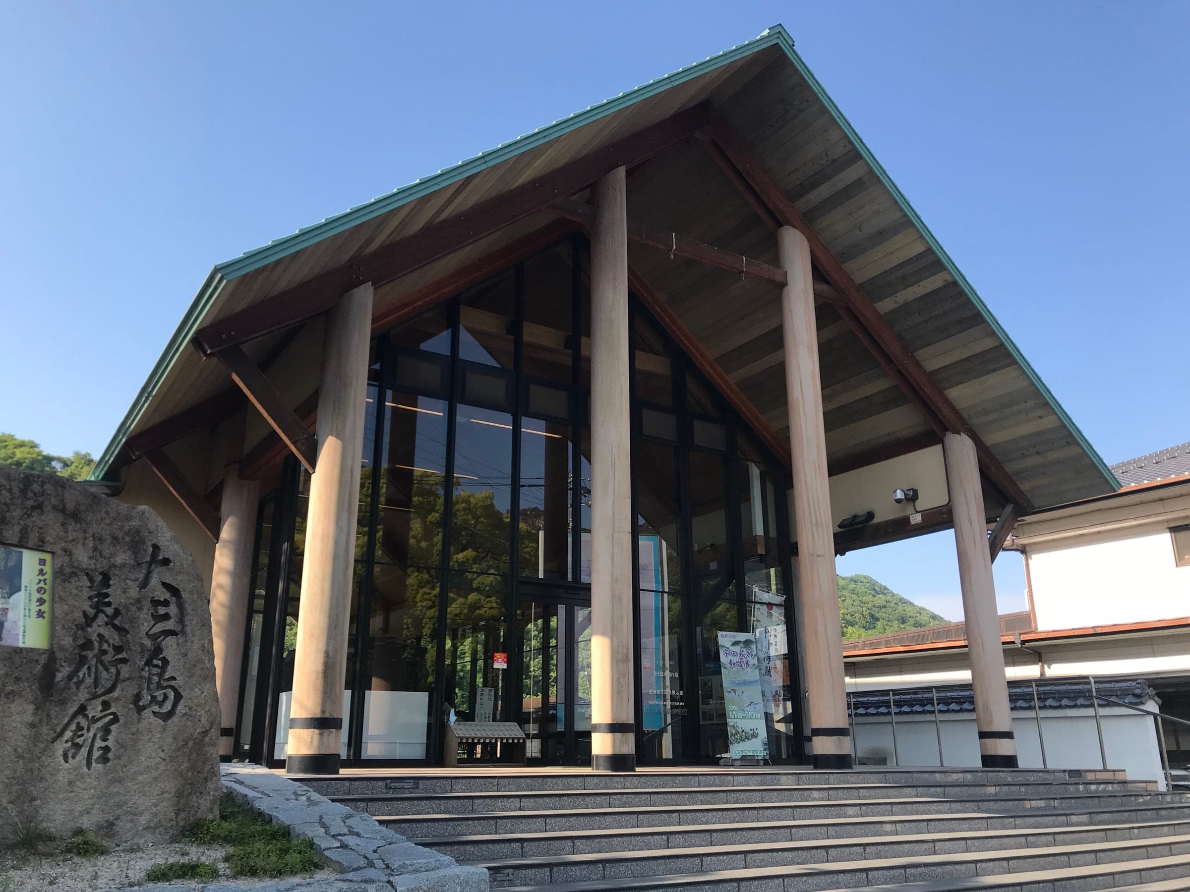 Tall timber columns frame the glass entrance of the Omishima Museum of Art.