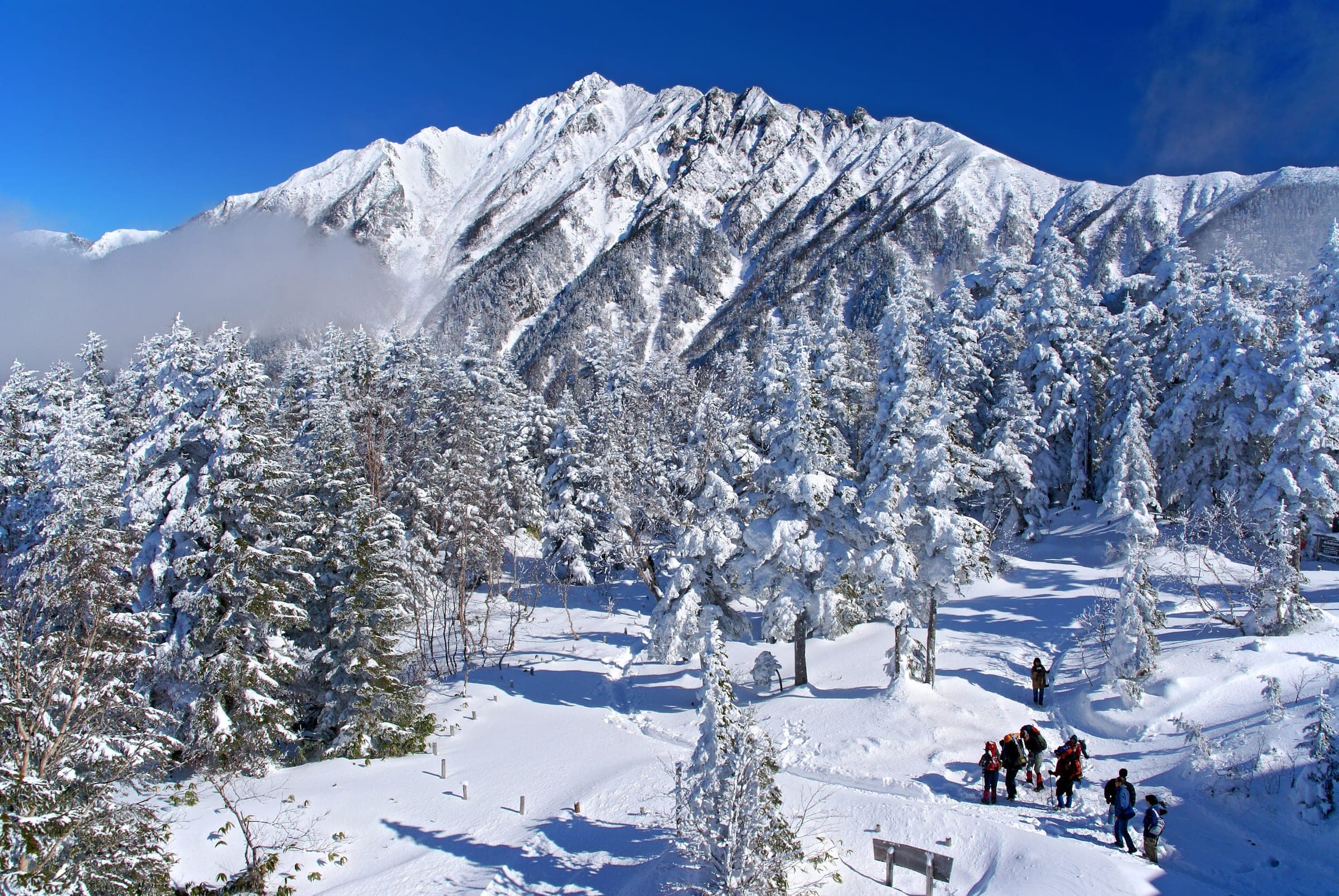 Hikers cross fresh snow below Mount Nishihotaka near Nishihotaka-guchi station at the top of the Shin-Hotaka Ropeway