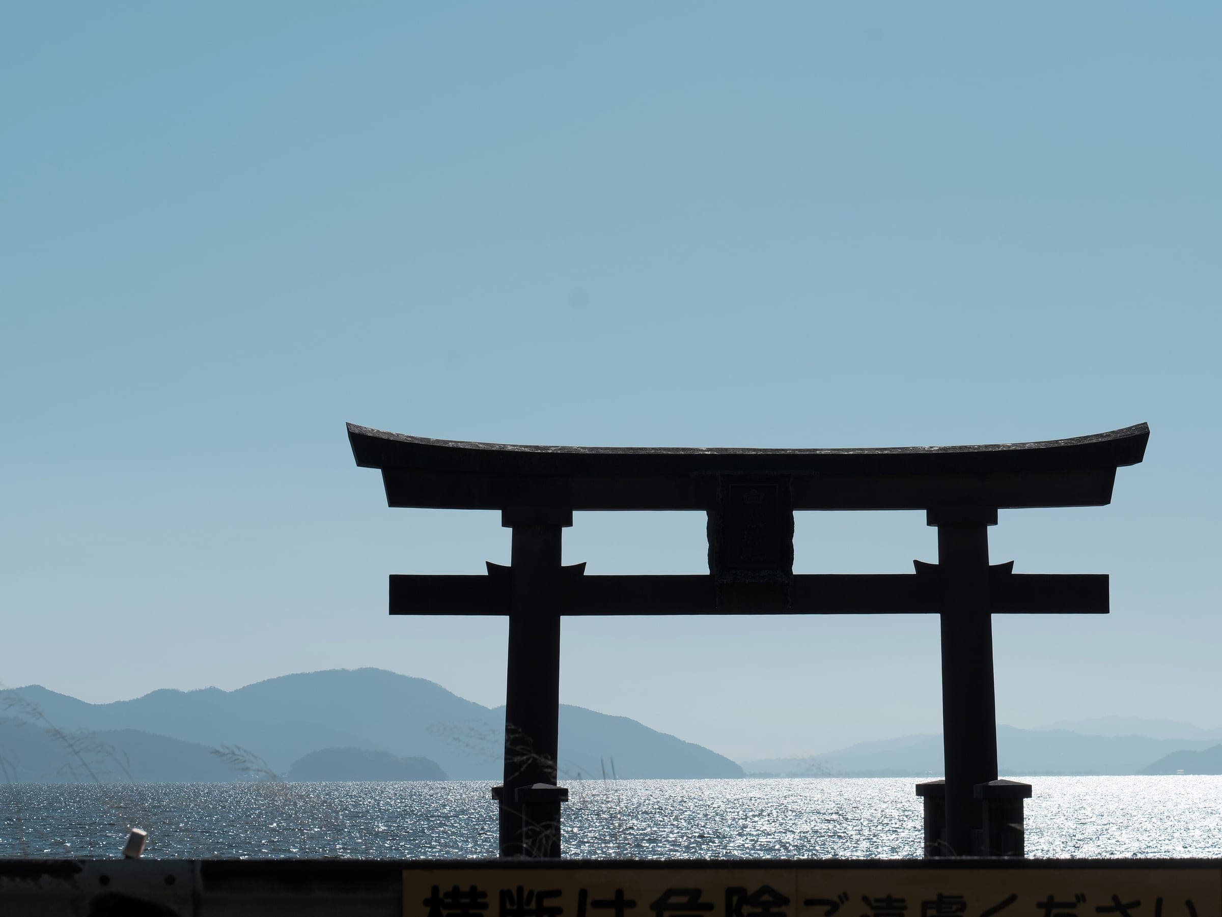 The Shirahige torii stands dark against the bright lake and far shore on a January afternoon