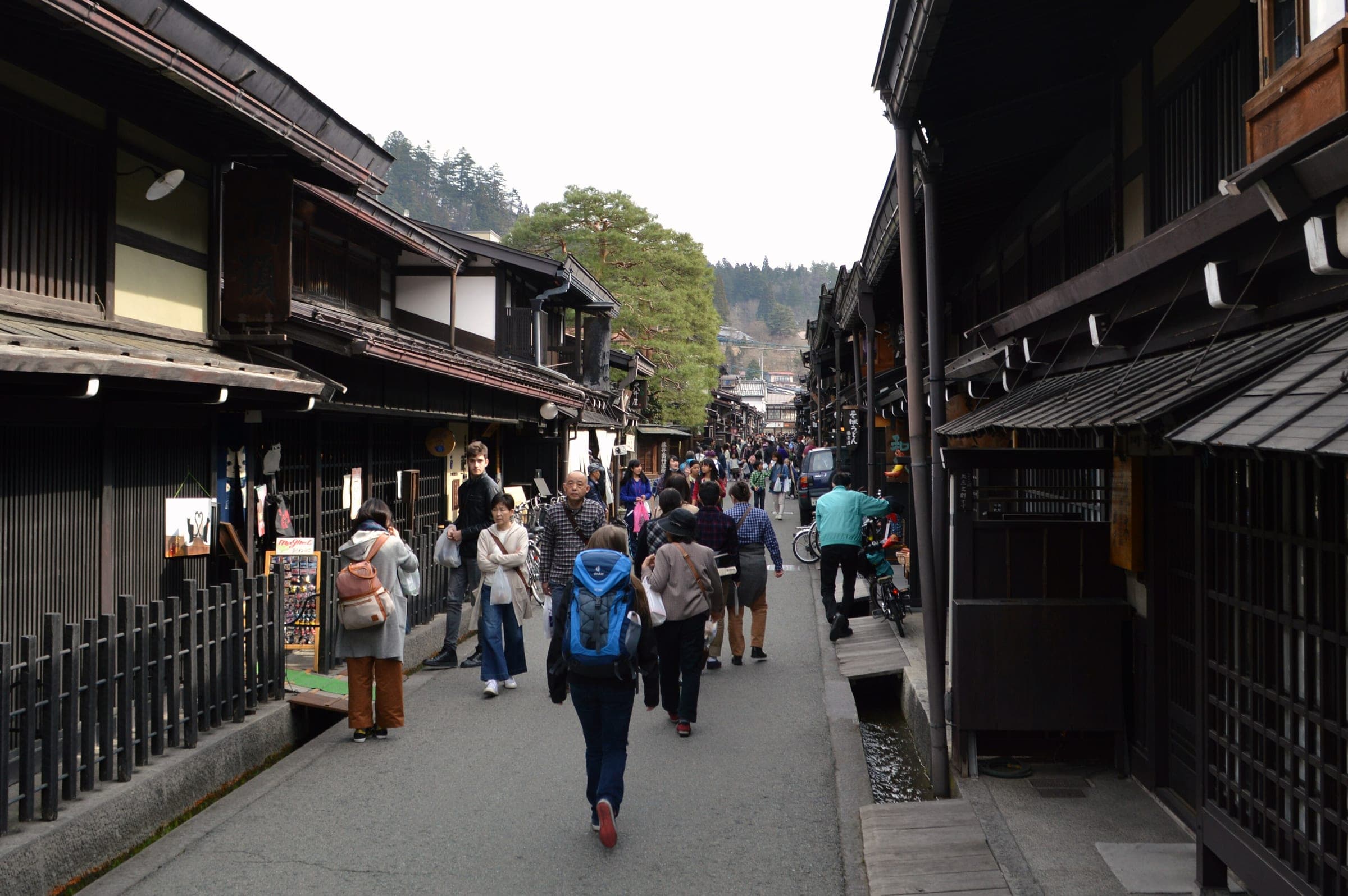 Visitors stroll Kami-sannomachi between dark wooden merchant houses in Takayama's old town