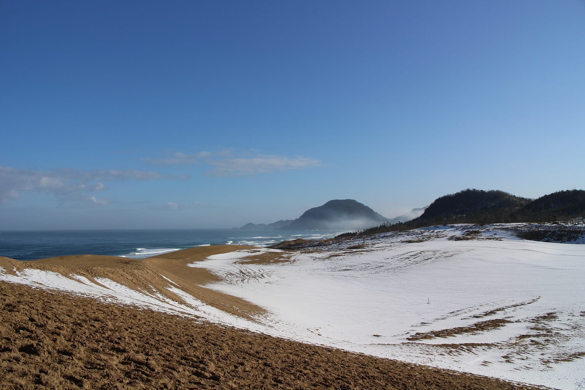Snow lies across the Tottori Sand Dunes above the Sea of Japan on a clear January day