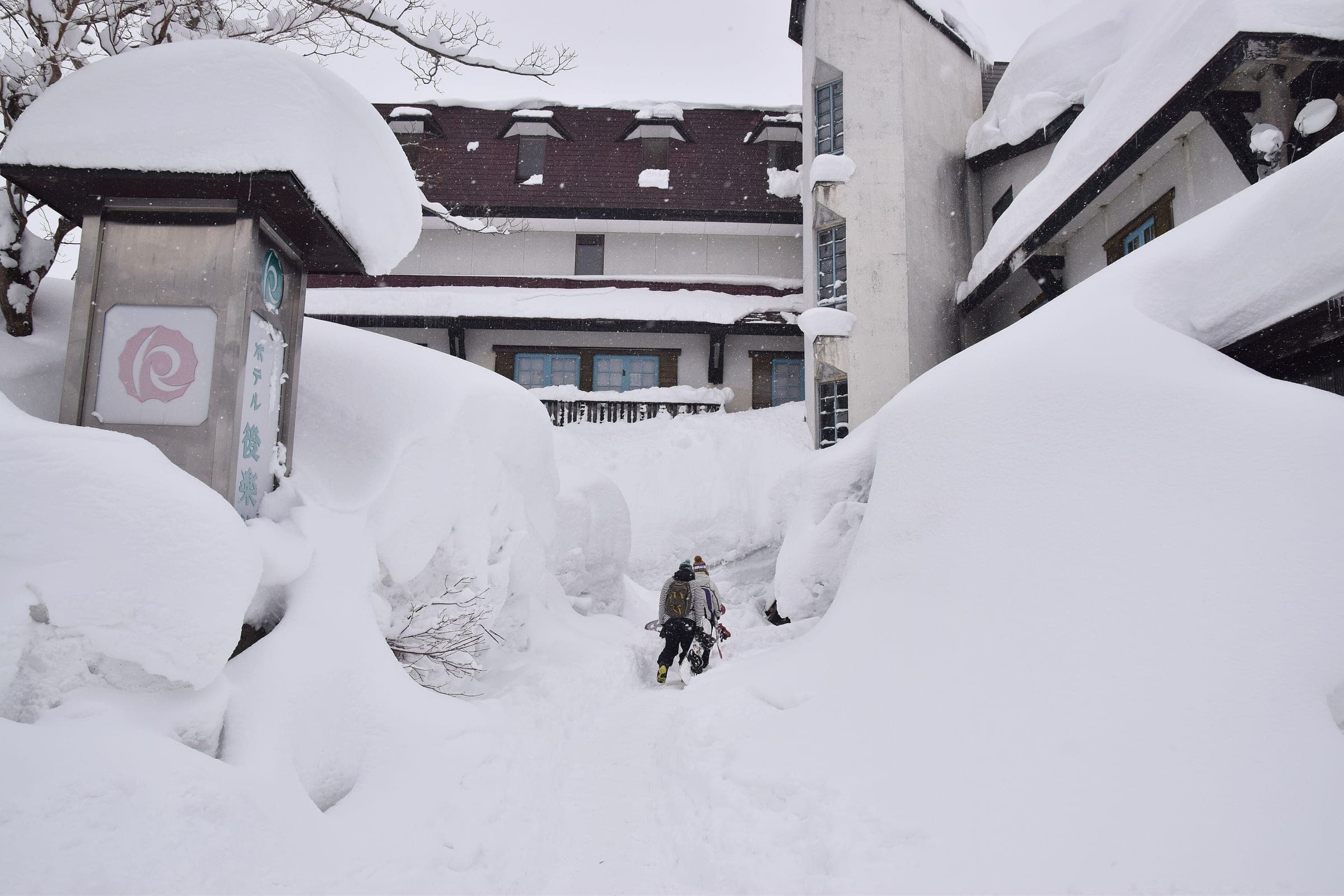 A skier walks a lane cut through head-high snowbanks between inns at Akakura Onsen