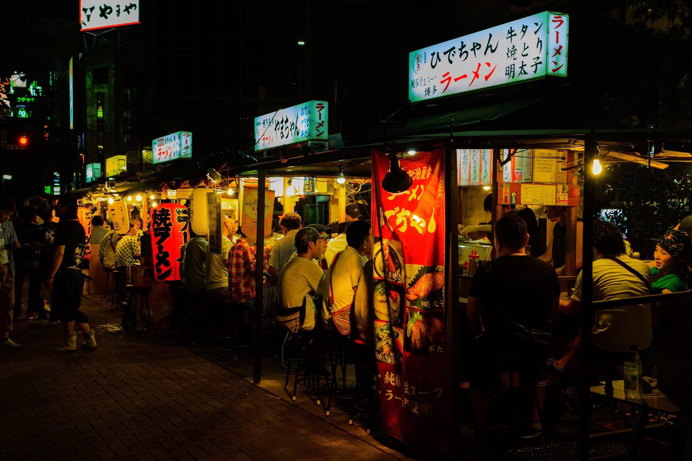 Diners crowd the lit ramen stalls of the Nakasu yatai along the river in Fukuoka at night.