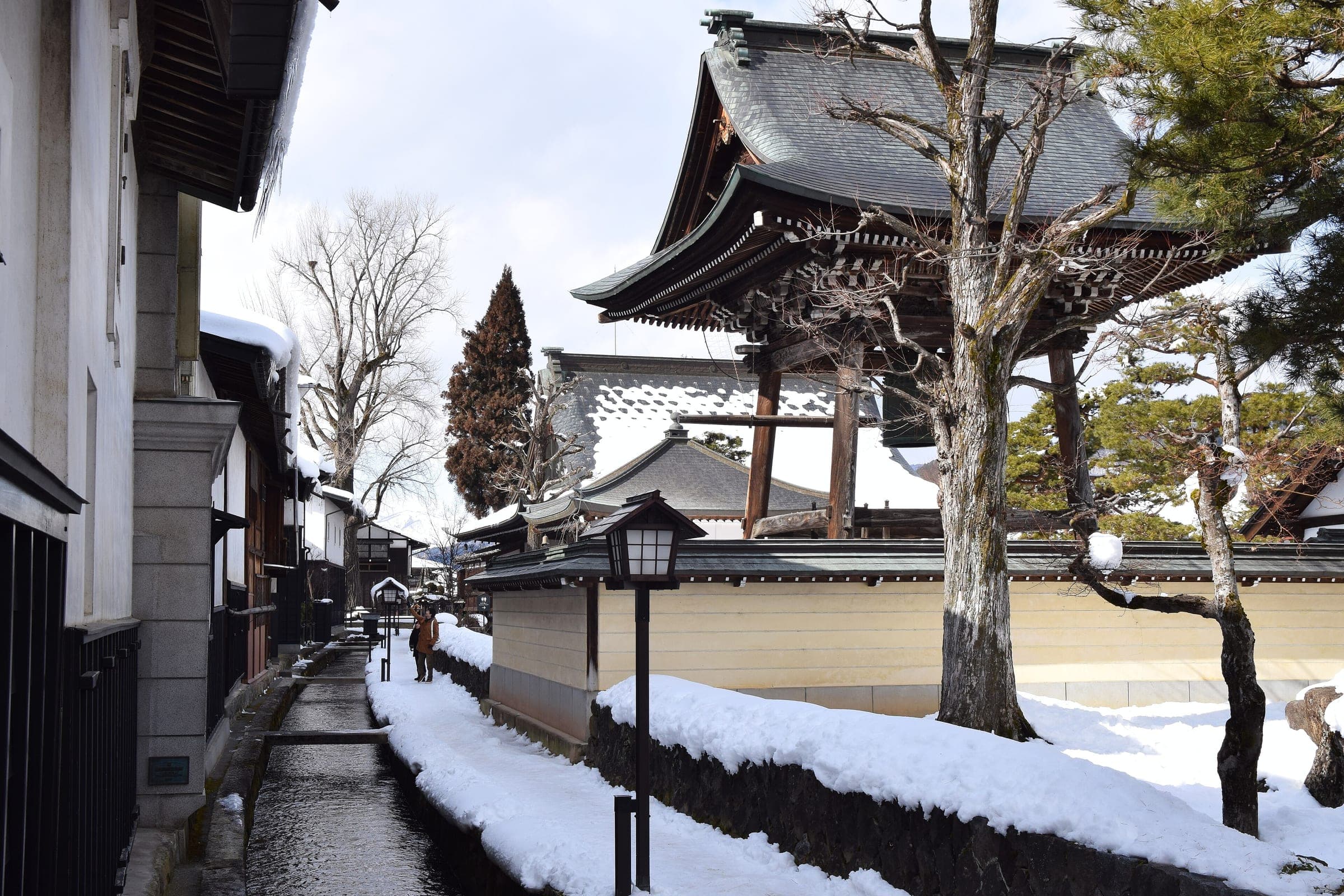 The Setogawa canal runs past snowy white walls and a temple gate in Hida-Furukawa in February