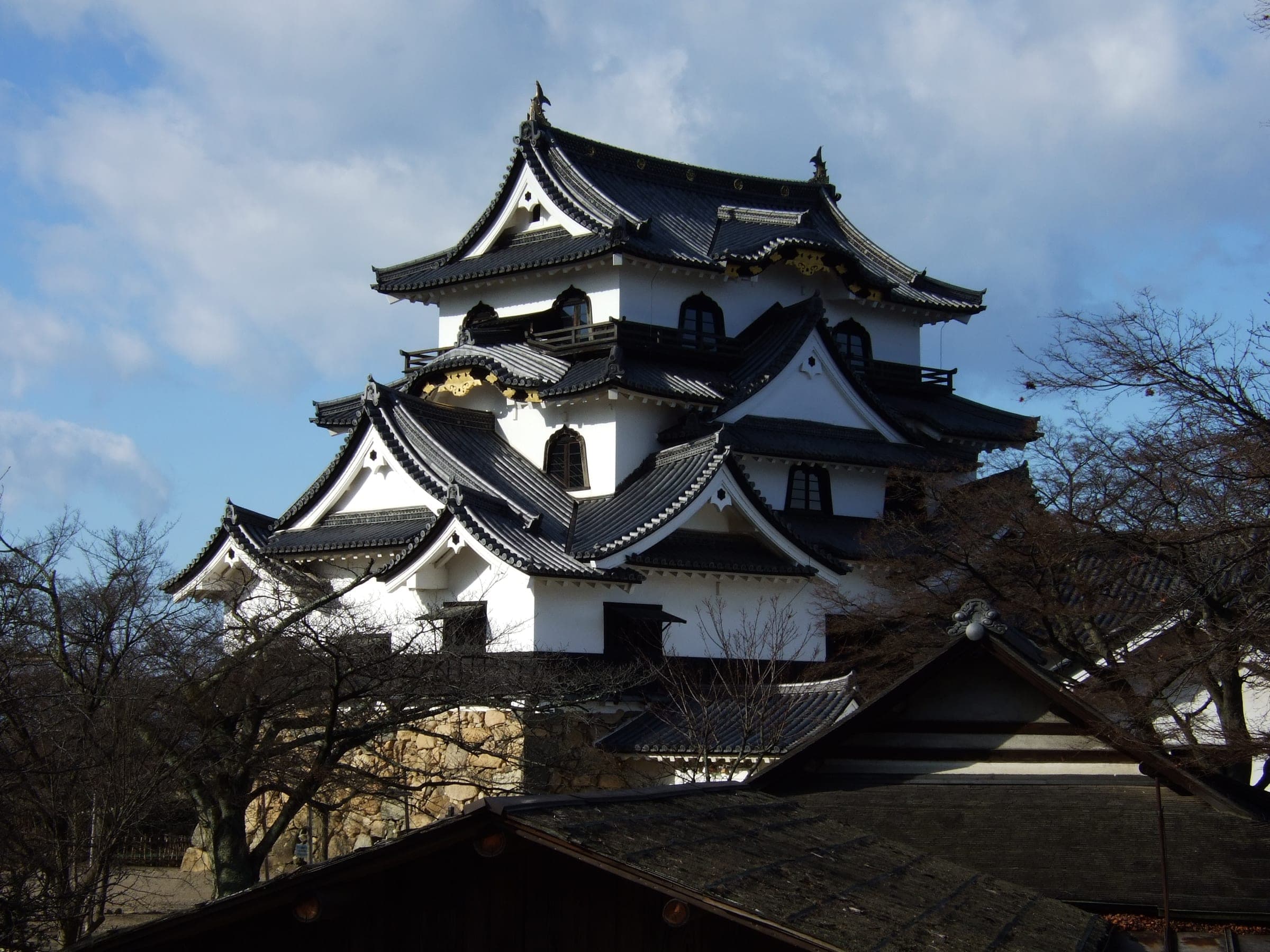 Hikone Castle's keep stands white against a spring sky above the old castle grounds