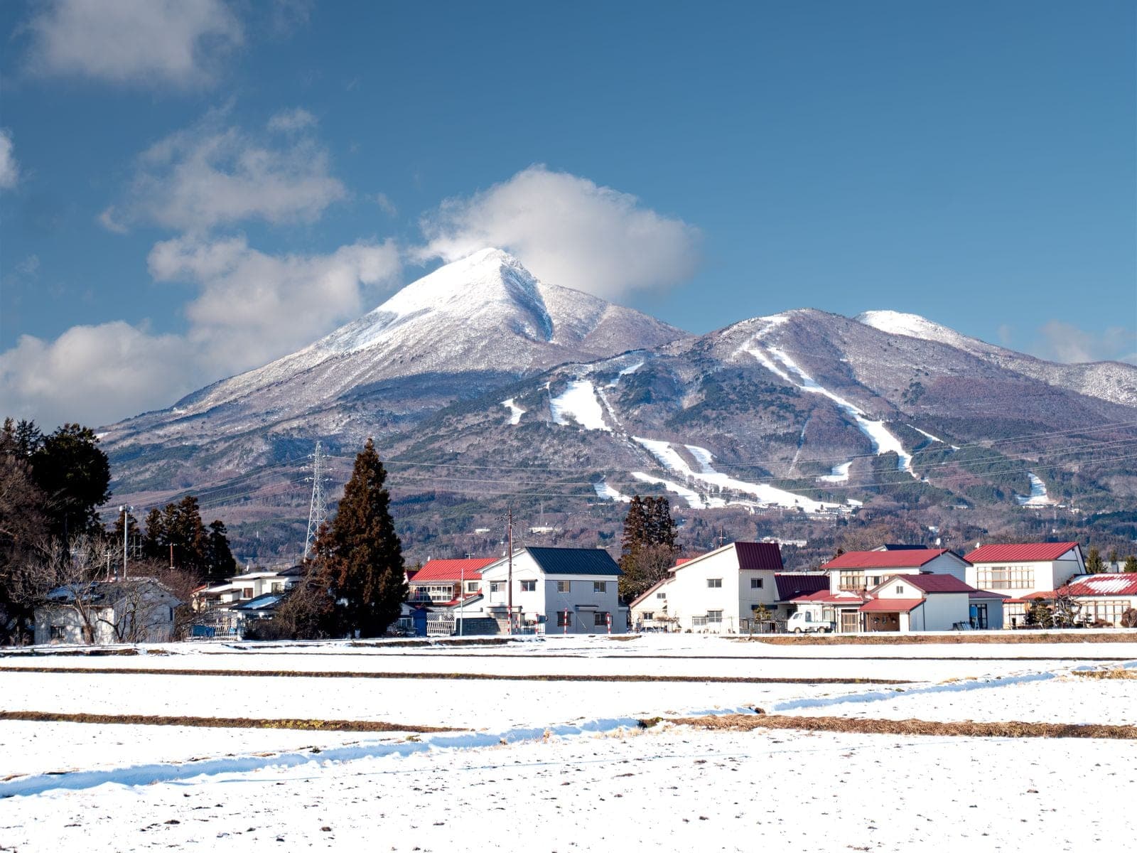 Mount Bandai rises white over snowy fields and red-roofed houses in Inawashiro in late December.