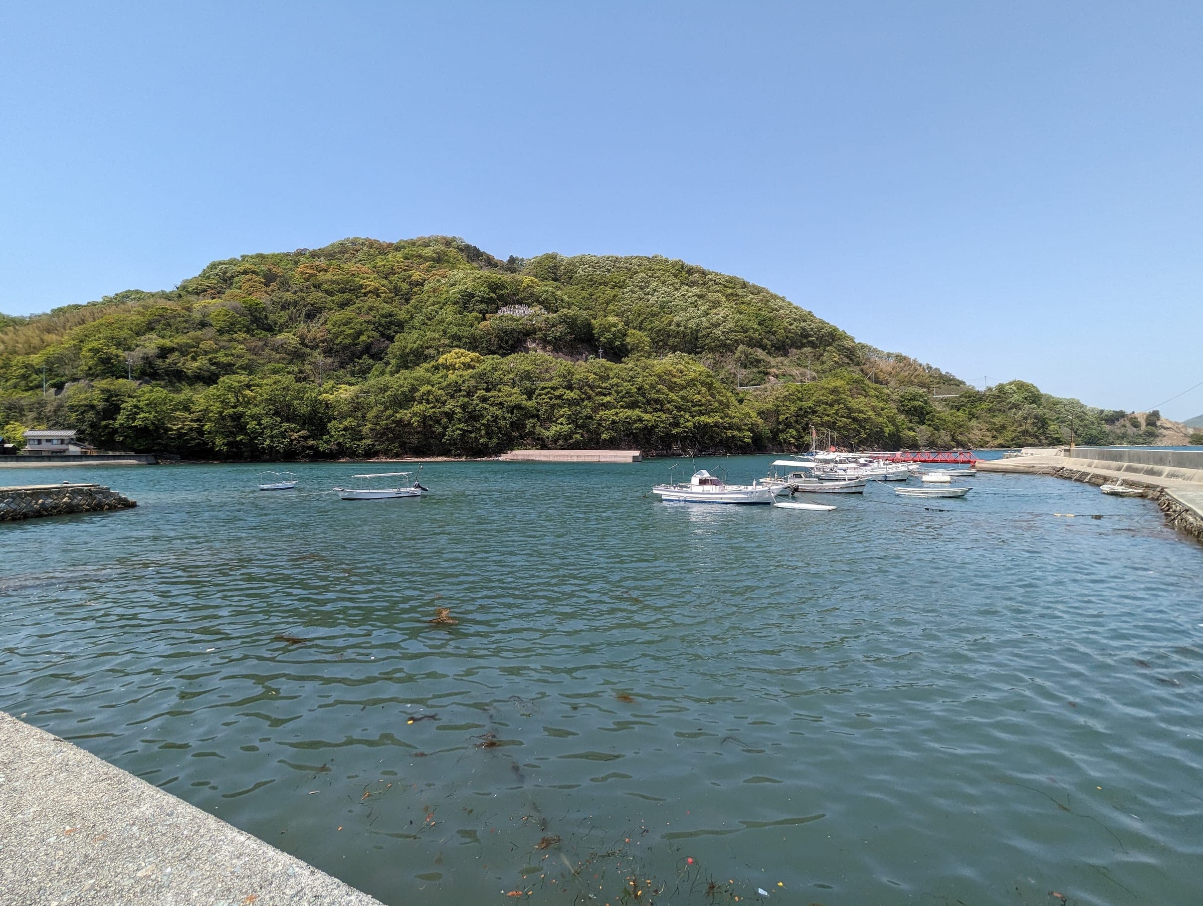 Small fishing boats sit moored in a green-walled cove on the north side of Innoshima.