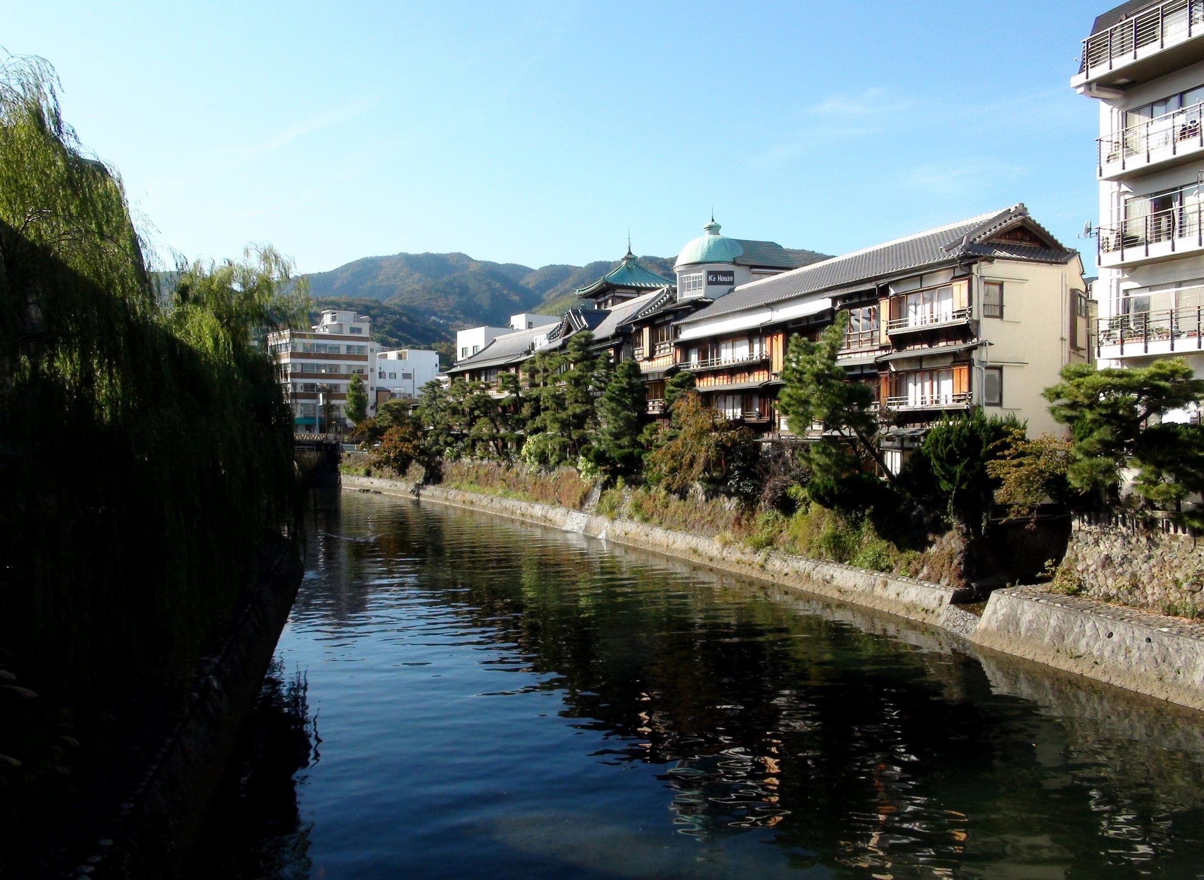 Old wooden ryokan and the Tokaikan tower line the Matsukawa River in Ito Onsen.