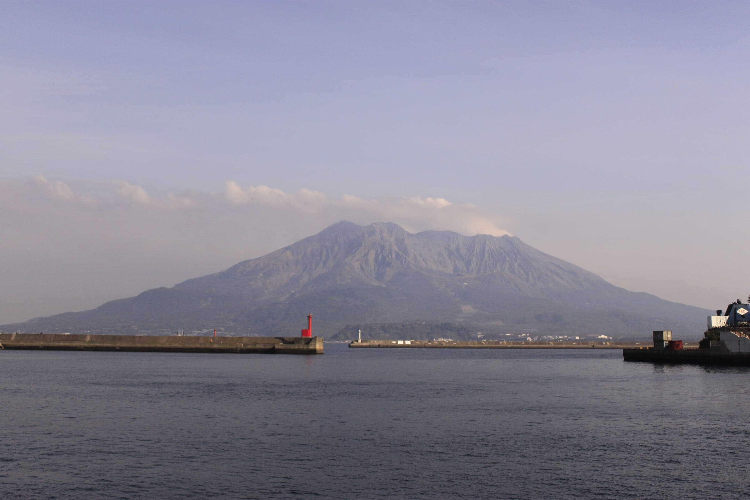 Sakurajima rises over the calm harbour water at Hamamachi in Kagoshima on a clear January day.