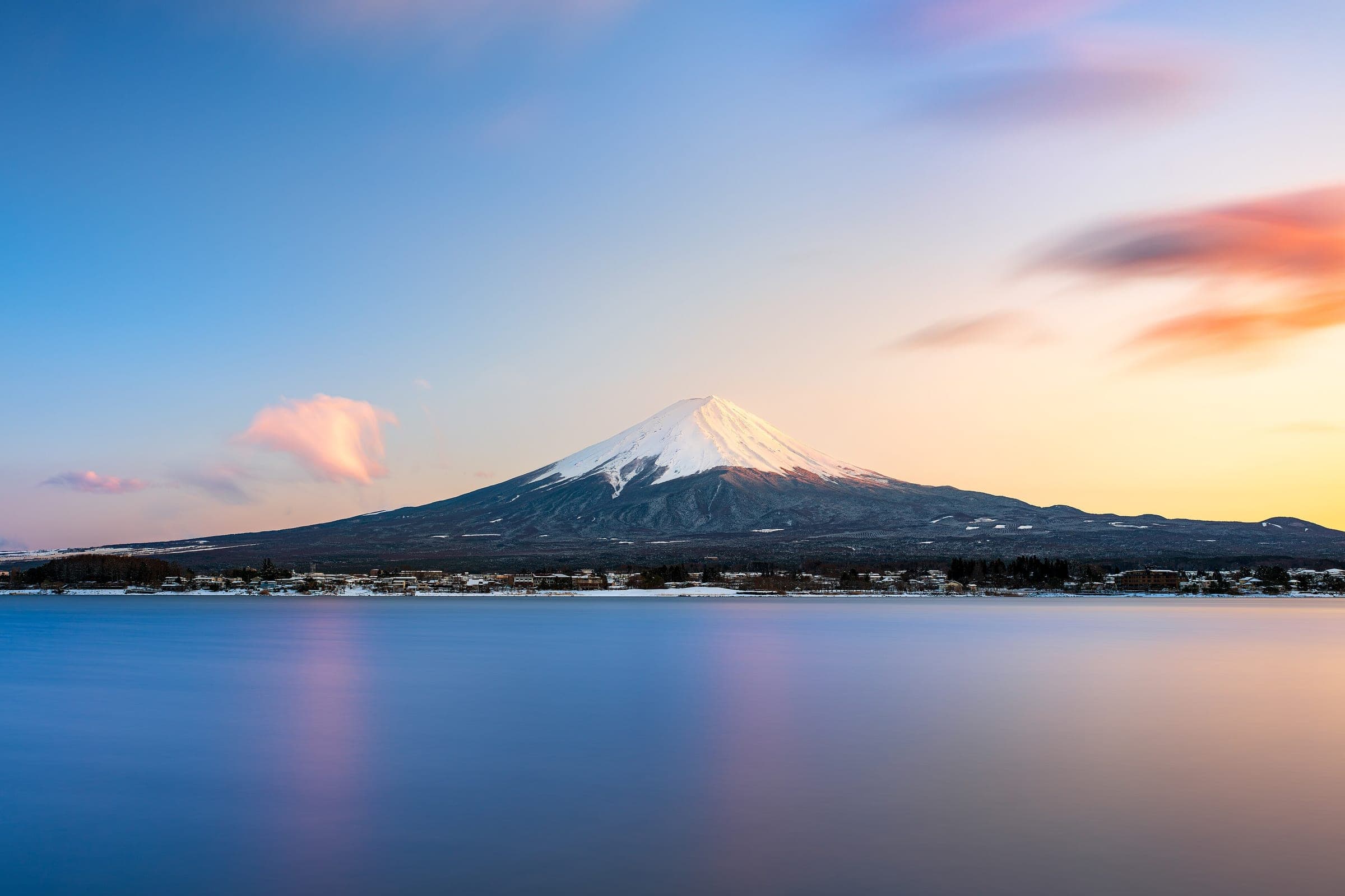Snow-capped Mt. Fuji catches the last light over the still water of Lake Kawaguchi in March.