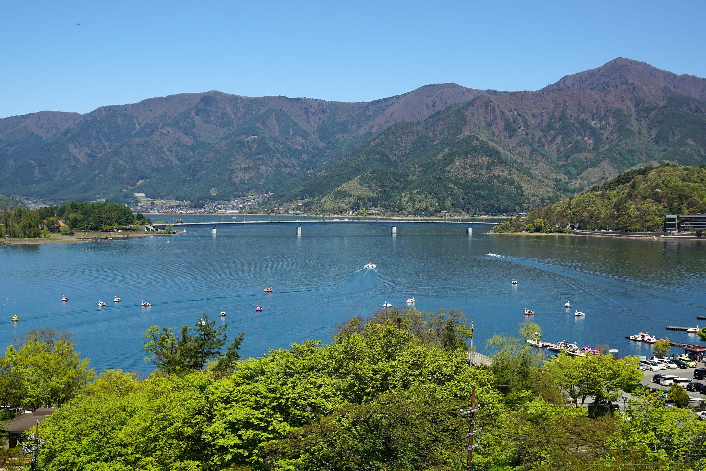 Lake Kawaguchi and its bridge spread below the Kachikachiyama Ropeway on a clear May day.