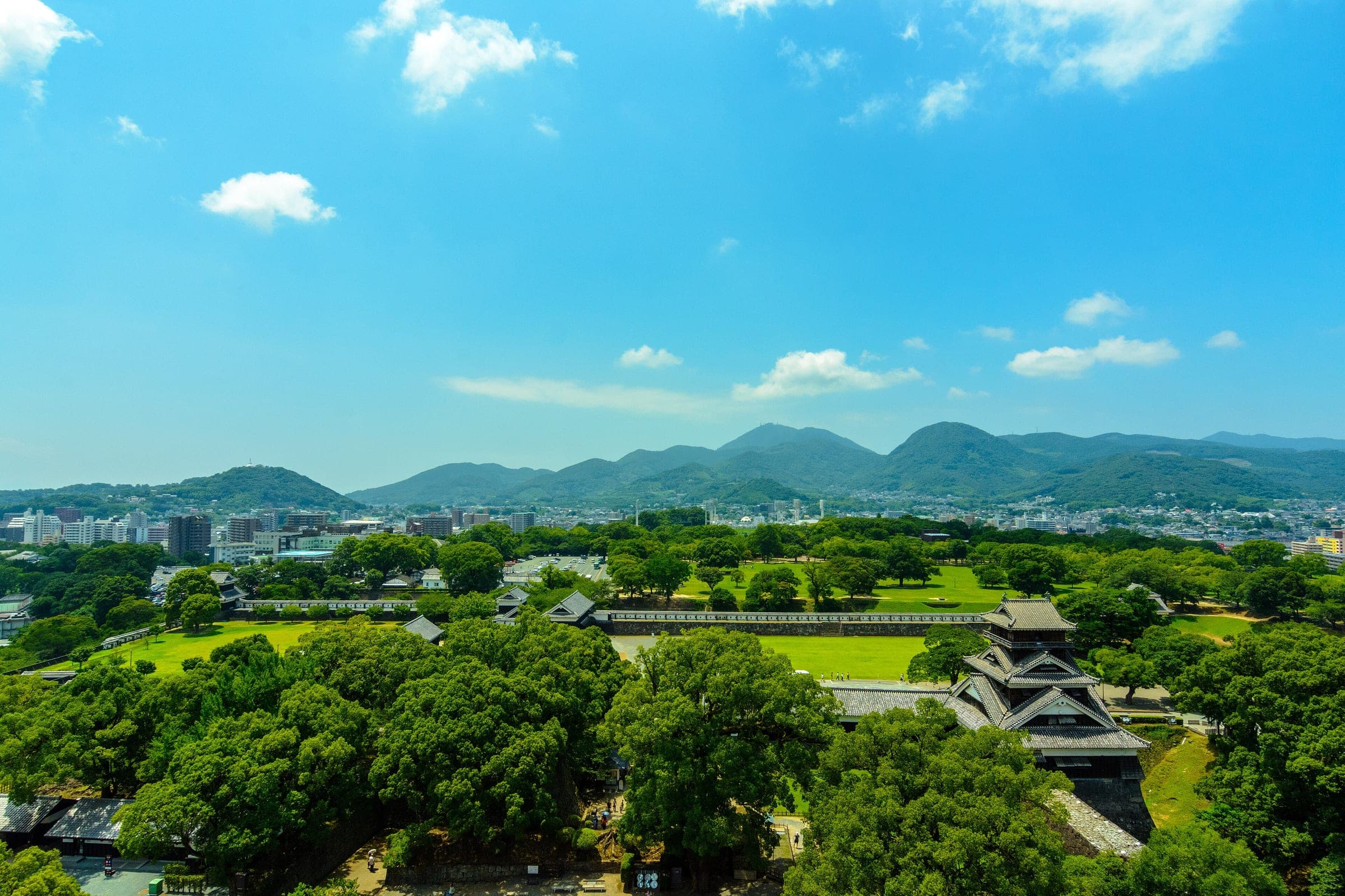From the castle keep you look over green castle grounds and Kumamoto city to the hills in the west.