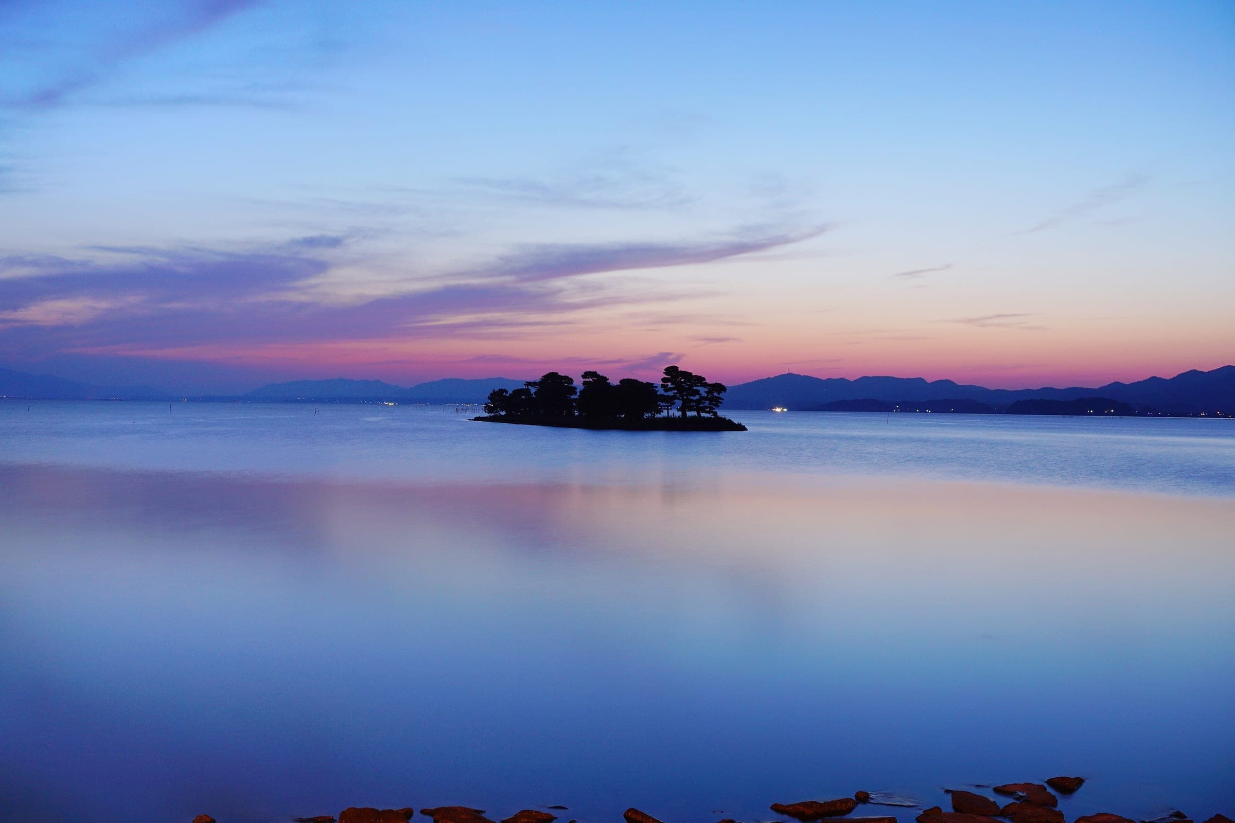 Yomegashima islet sits on Lake Shinji under a pink sky after sunset in Matsue