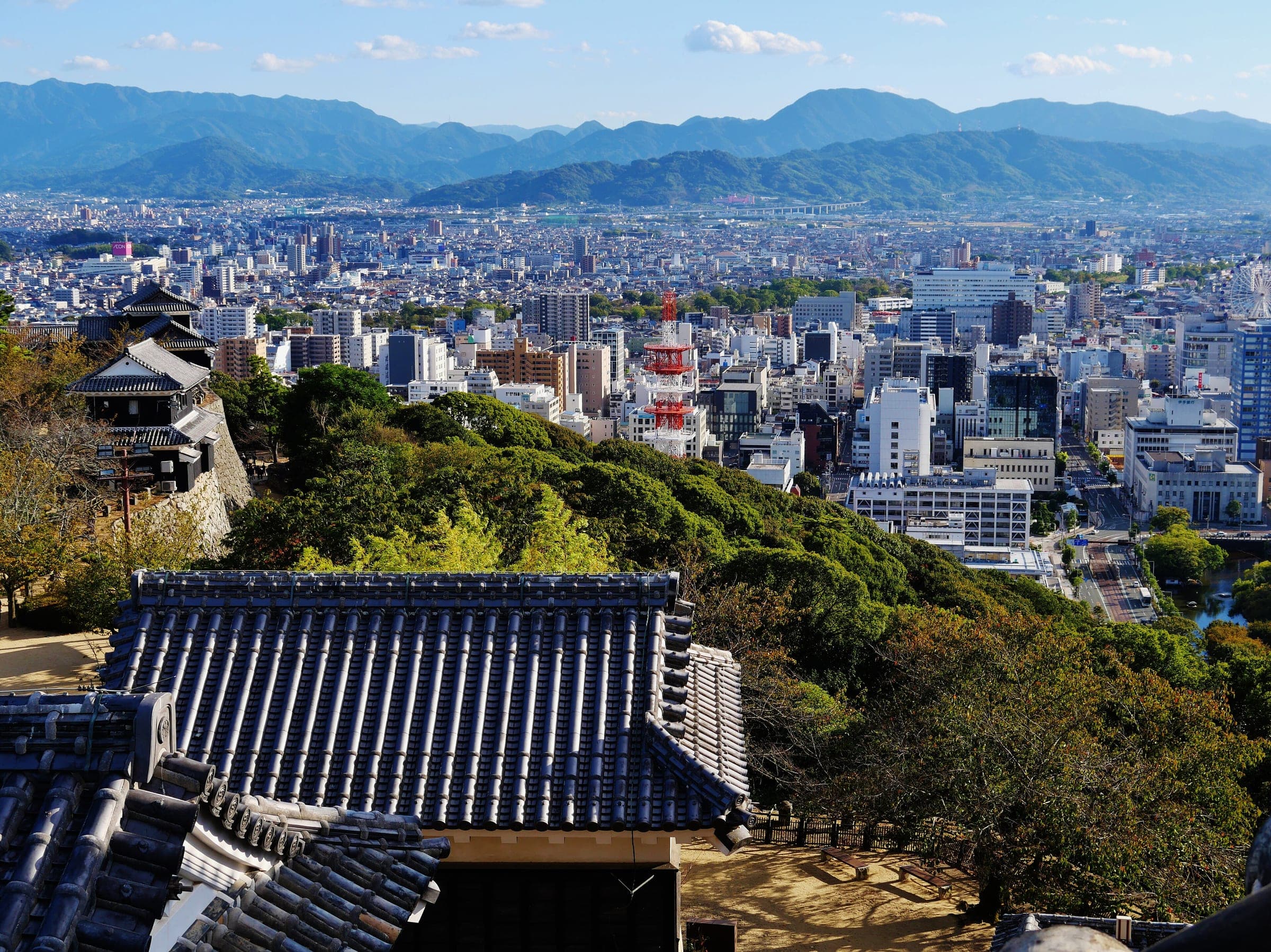 Matsuyama spreads toward the Shikoku mountains beyond the tiled roofs of the castle.