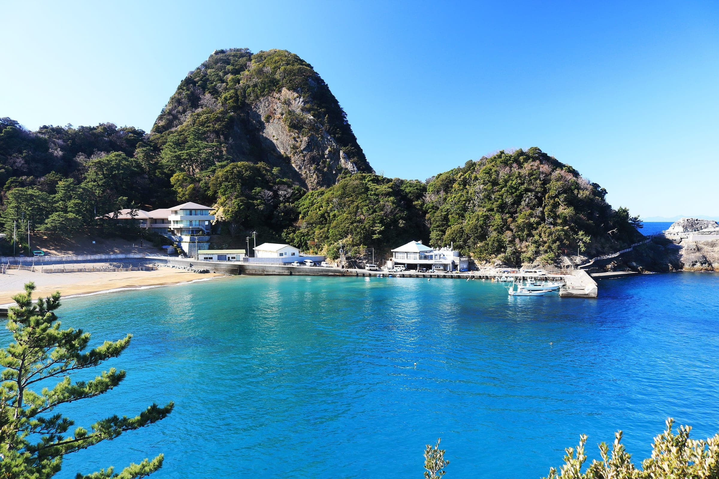 Mt. Eboshi rises over the clear blue cove and fishing port of Kumomi in Matsuzaki.