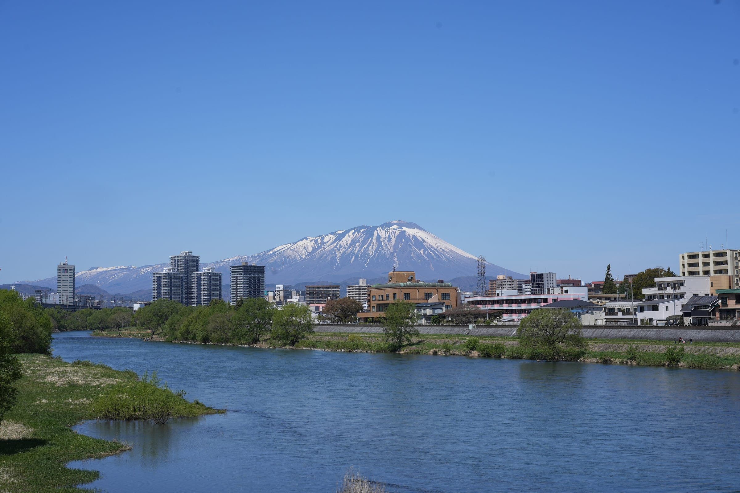 Snow-capped Mount Iwate rises behind the Morioka skyline across the Kitakami River.