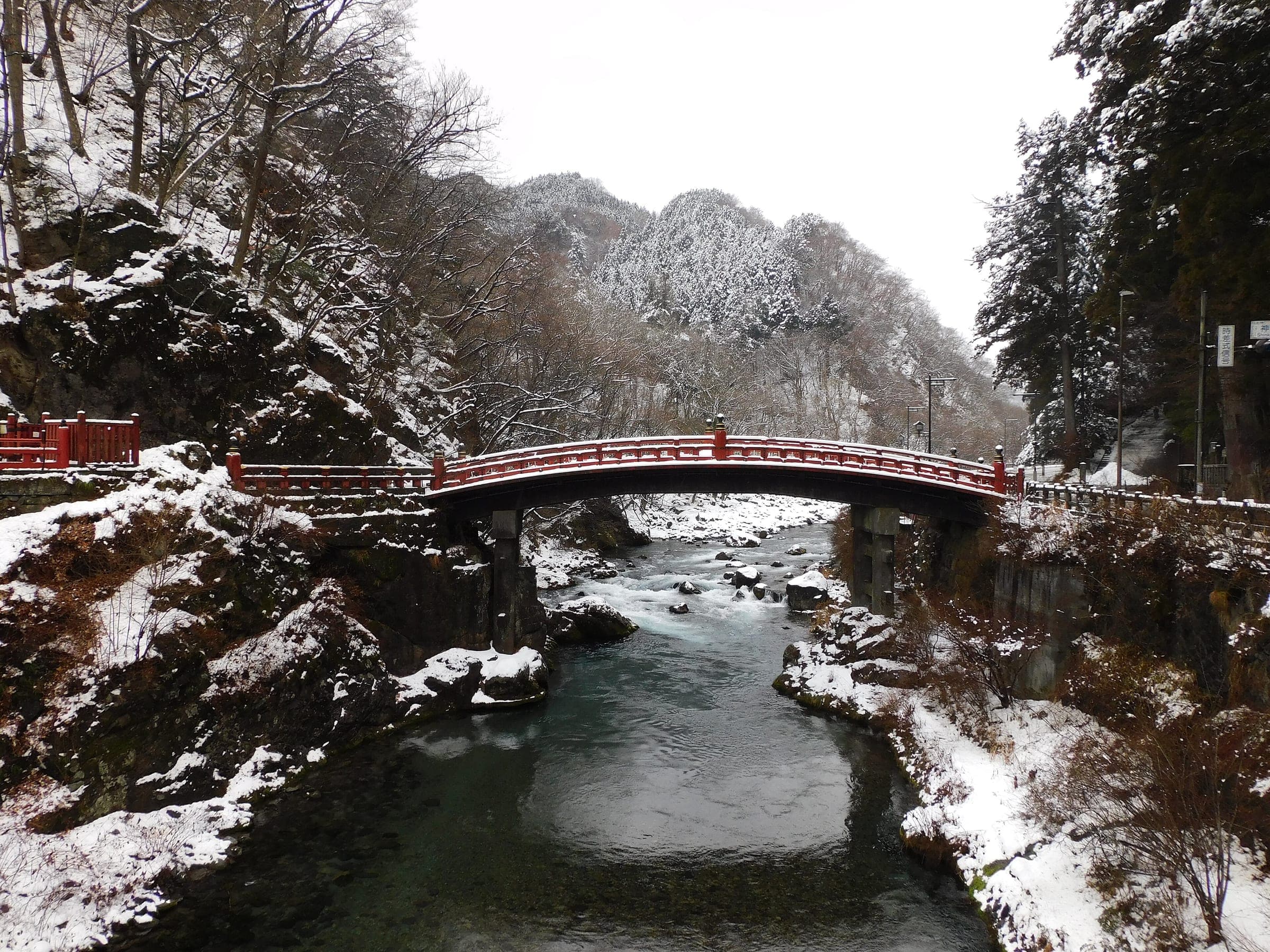 The Shinkyo bridge spans the Daiya River below snowy hills in Nikko in January