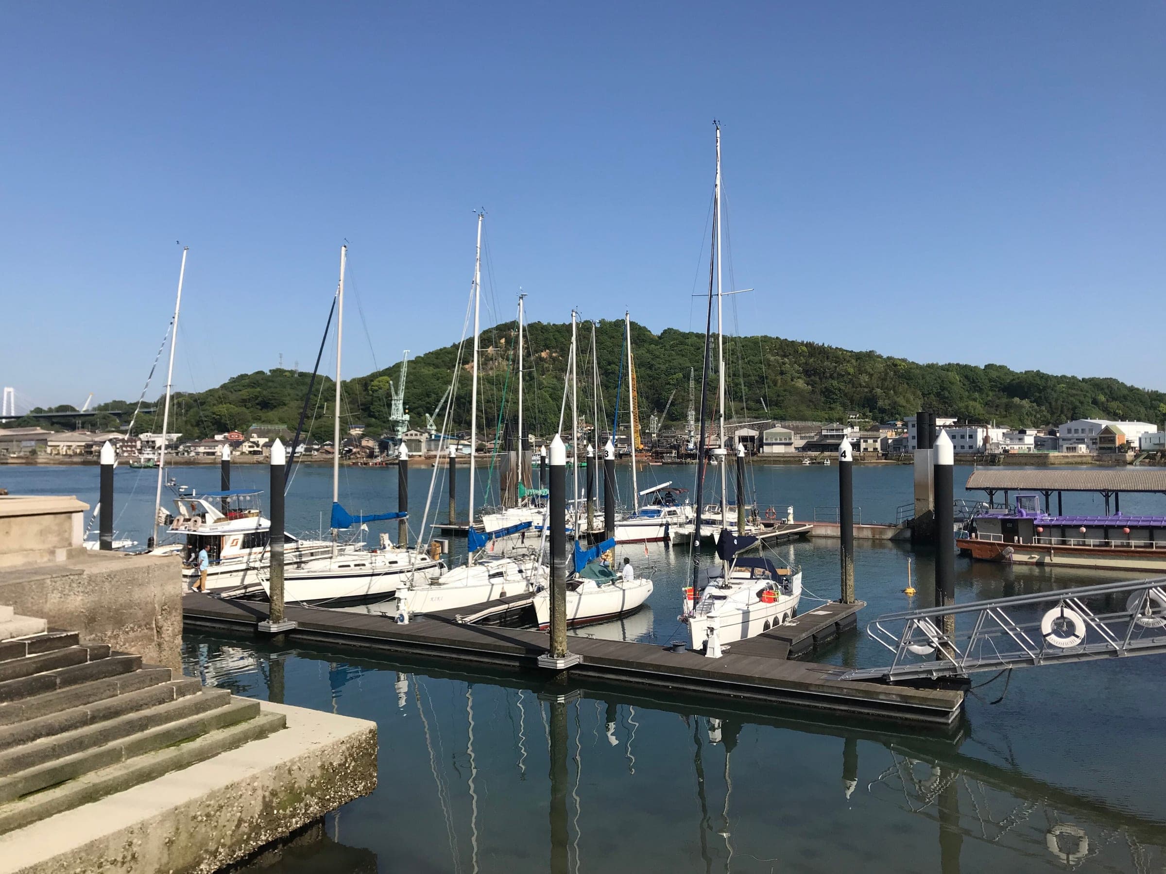 Yachts tie up at Onomichi's visitor pier across the channel from the hills of Mukaishima.