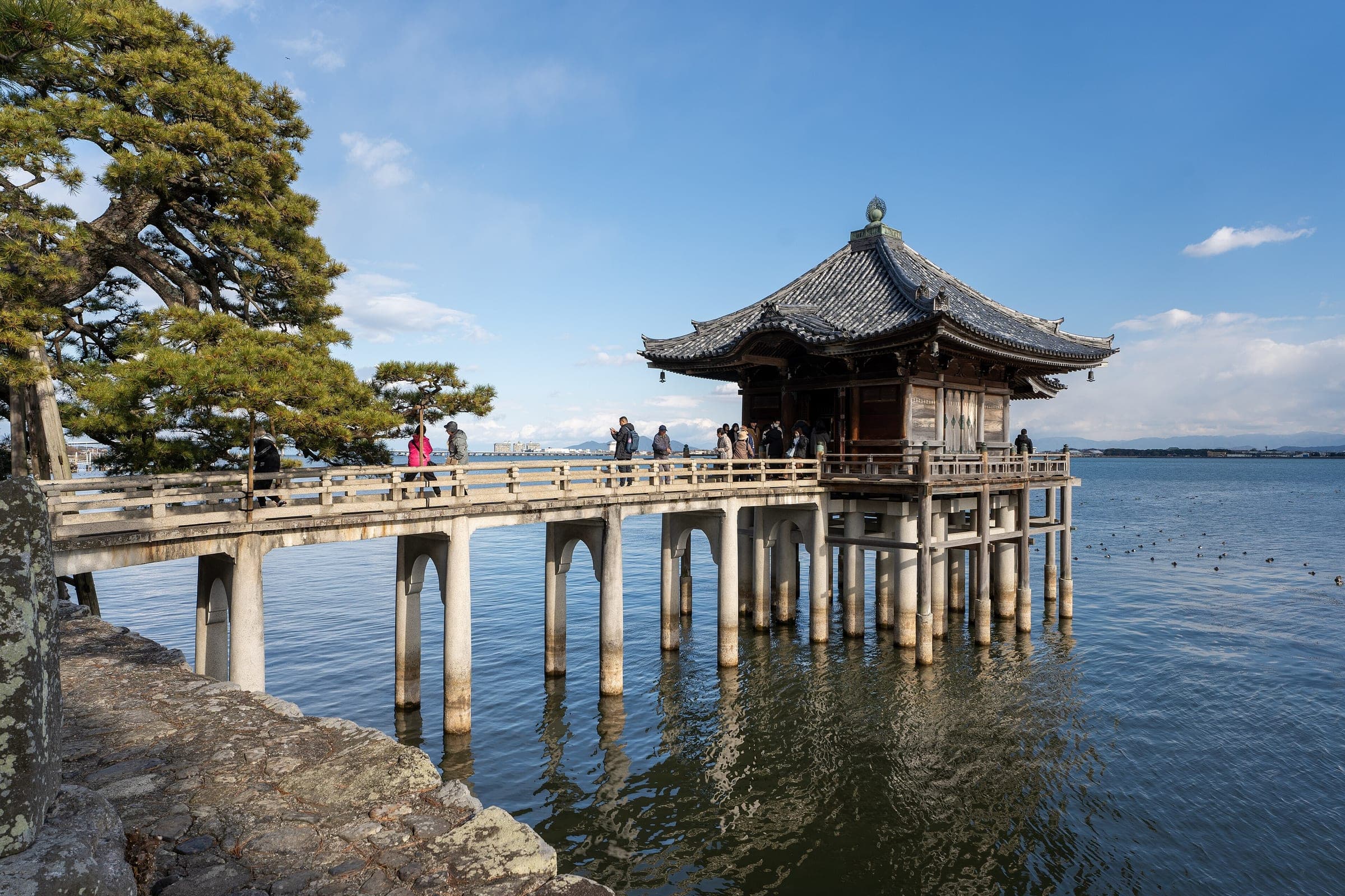 Visitors cross the wooden walkway to the Ukimido hall on its stilts over Lake Biwa at Katata in Otsu