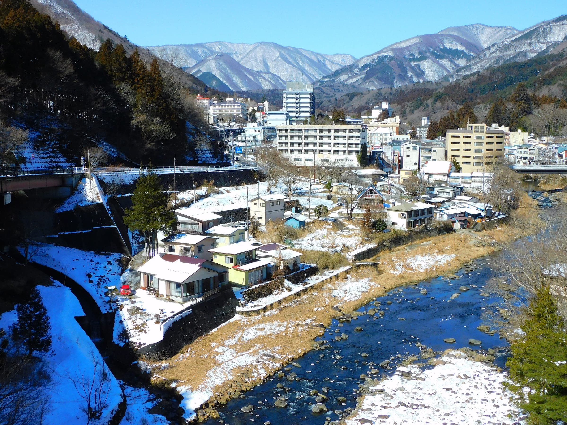 Inns line the Hoki River at Hataori in Shiobara Onsen below snowy peaks in February