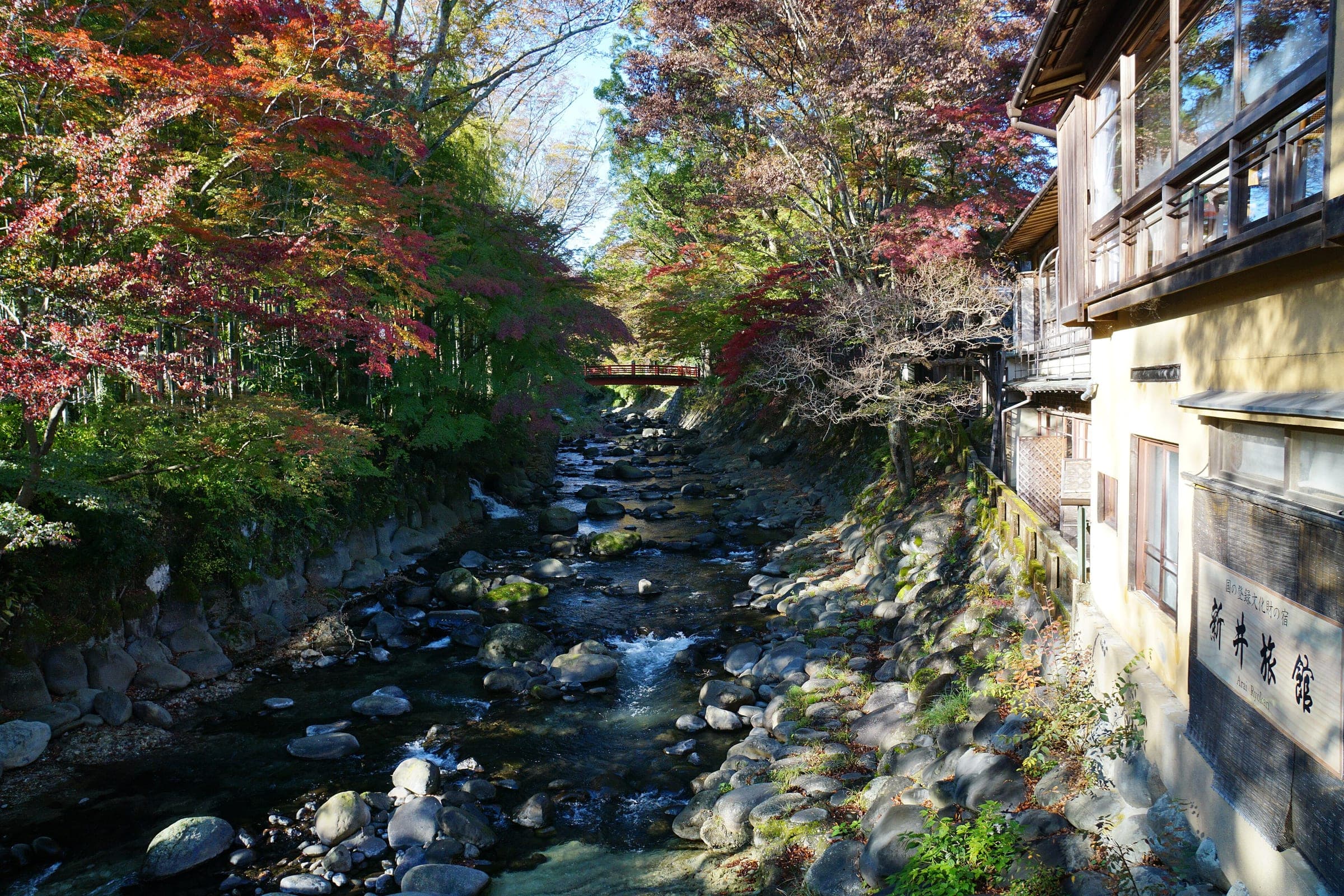 Autumn maples hang over the rocky Katsura River beside an old ryokan in Shuzenji.