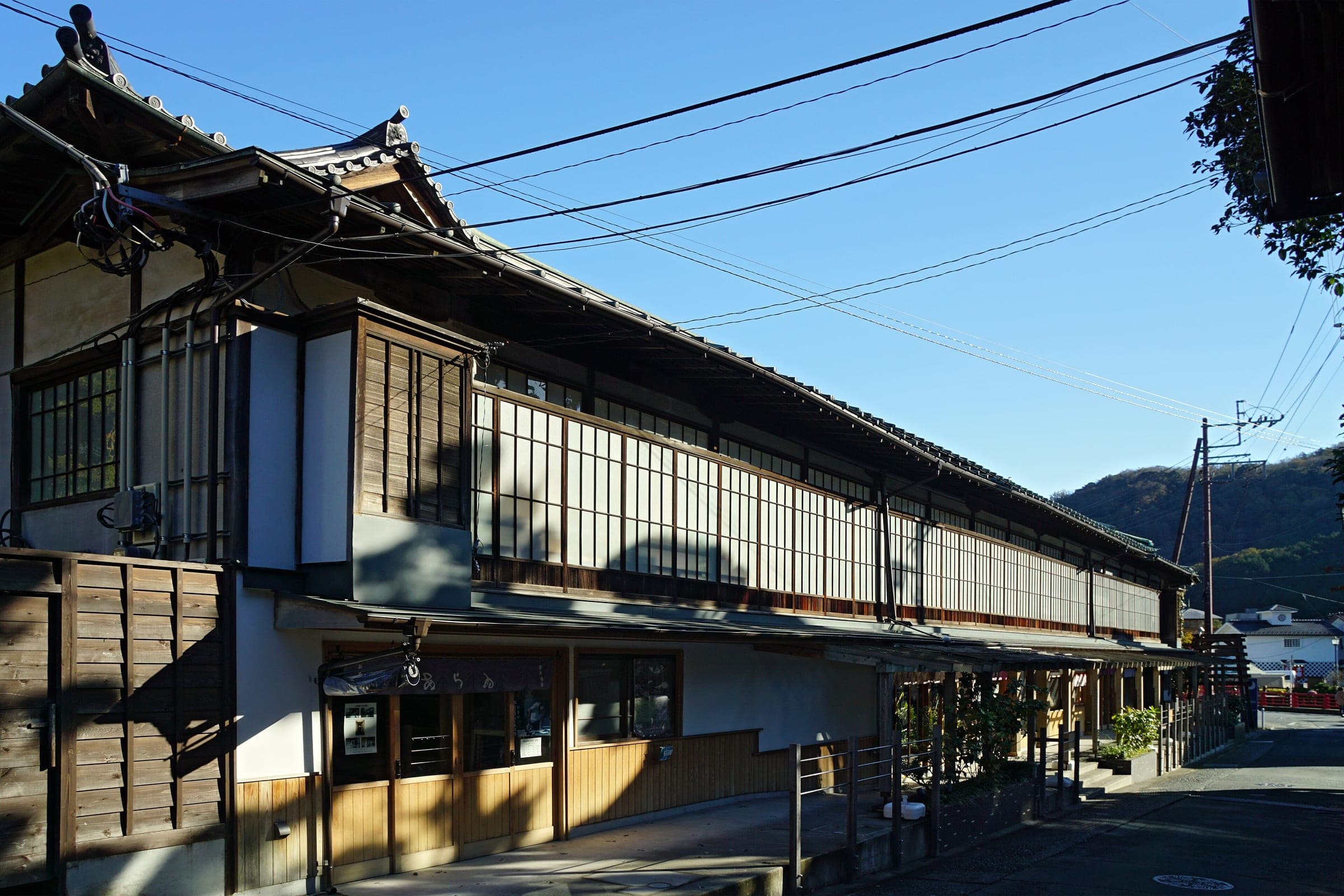 A long two-storey wooden ryokan with glass-panelled galleries lines a lane in Shuzenji.